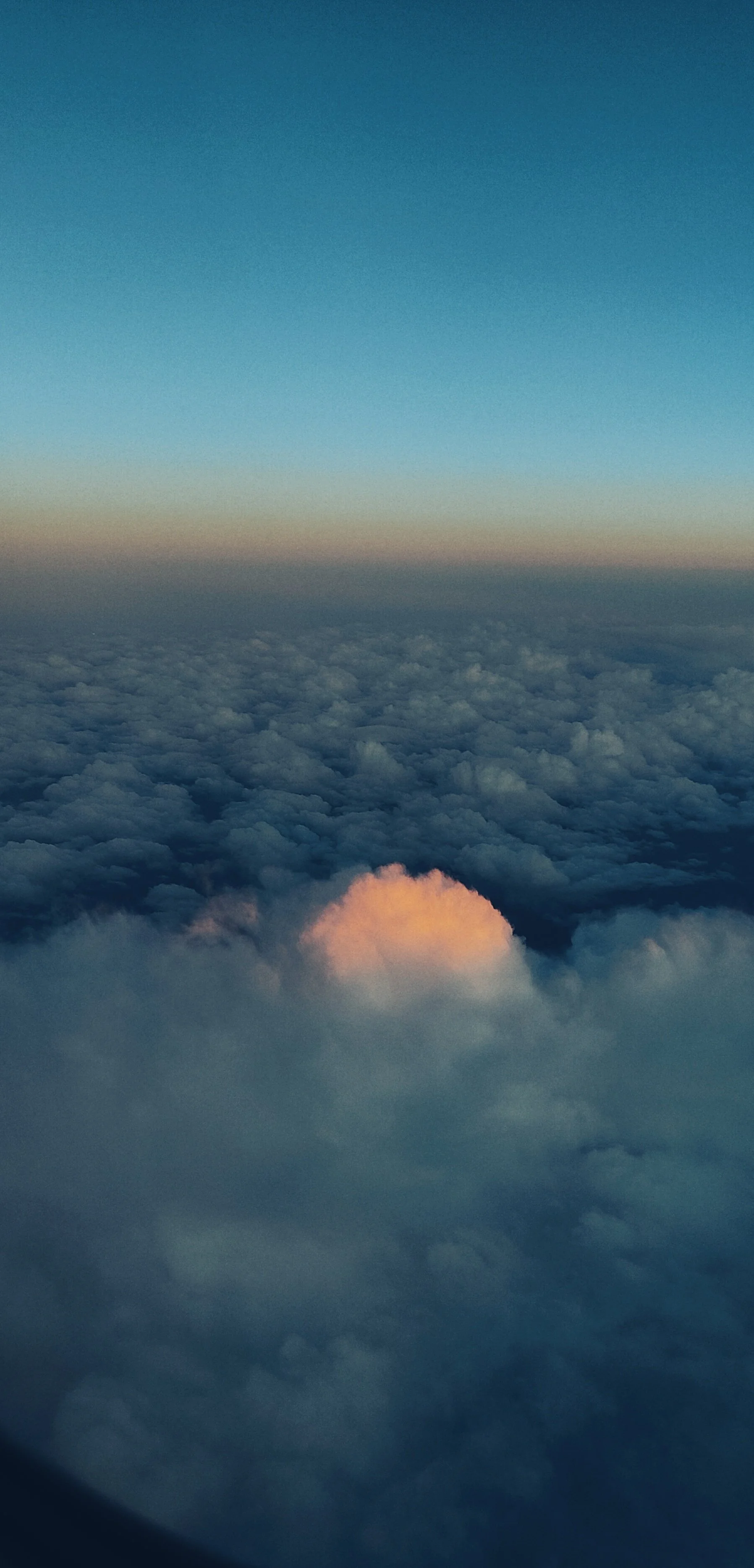 Ciel vu d'un avion montrant la couronne de nuages et un coucher ou lever de soleil derrière des nuages.