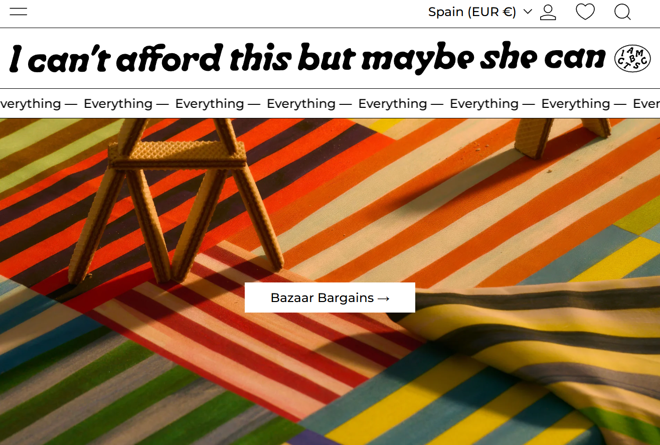 Une table recouverte d'un tissu à rayures colorées, avec un petit modèle en biscuit de sable représentant une chaise et une pièce de papier avec une inscription "Bazaar Bargains".