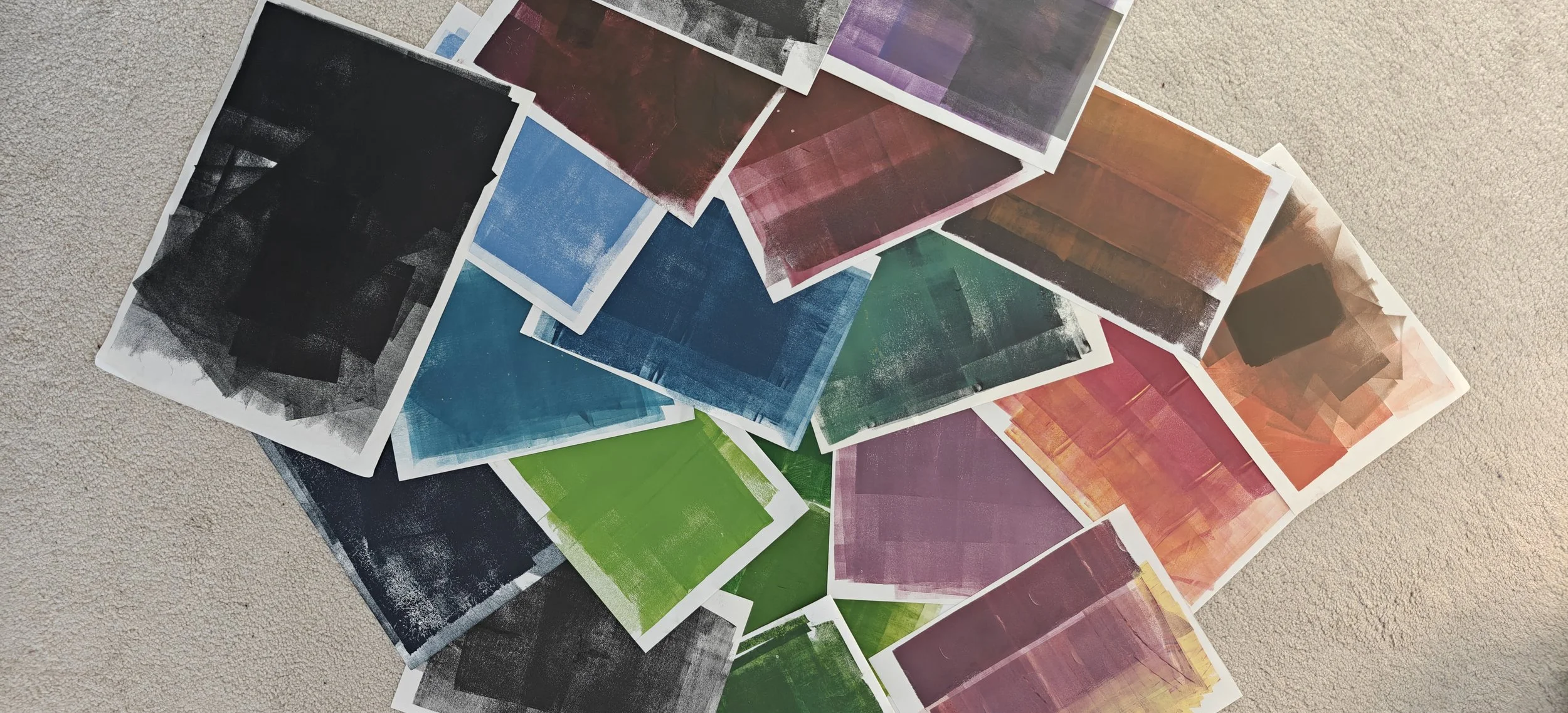 Échantillons de peintures ou de couleurs en miniatures dispersés sur une surface beige, affichant une variété de teintes et de textures.