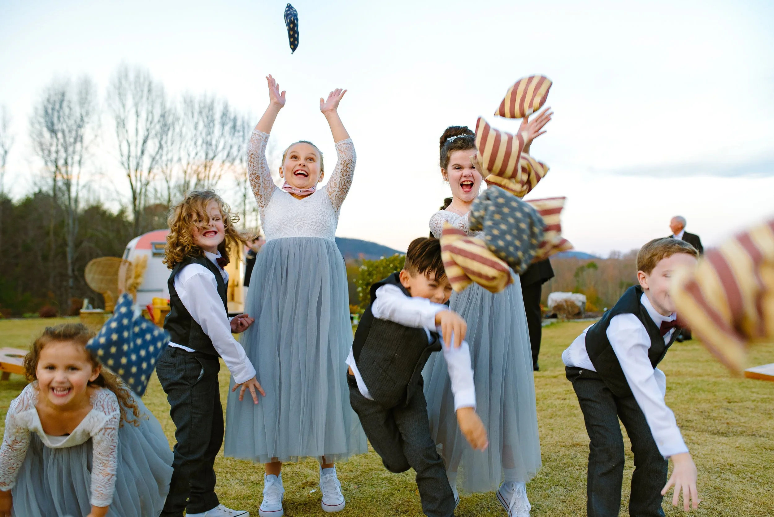 Flower girls and ring bearers throwing bean bags in the air at a North Georgia Wedding.  Wedding Photography by Sowing Clover Photography.