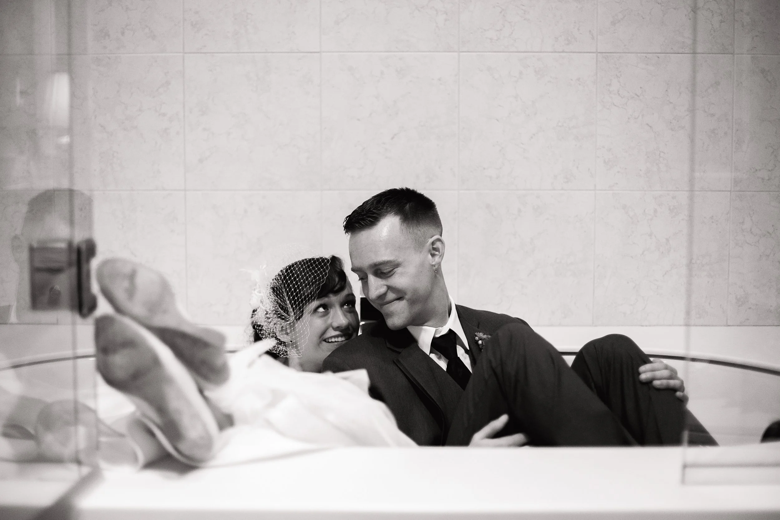 A black and white photo of a couple in wedding attire sitting in tub. wedding portrait in Atlanta, Wedding photography by Sowing Clover Photography.