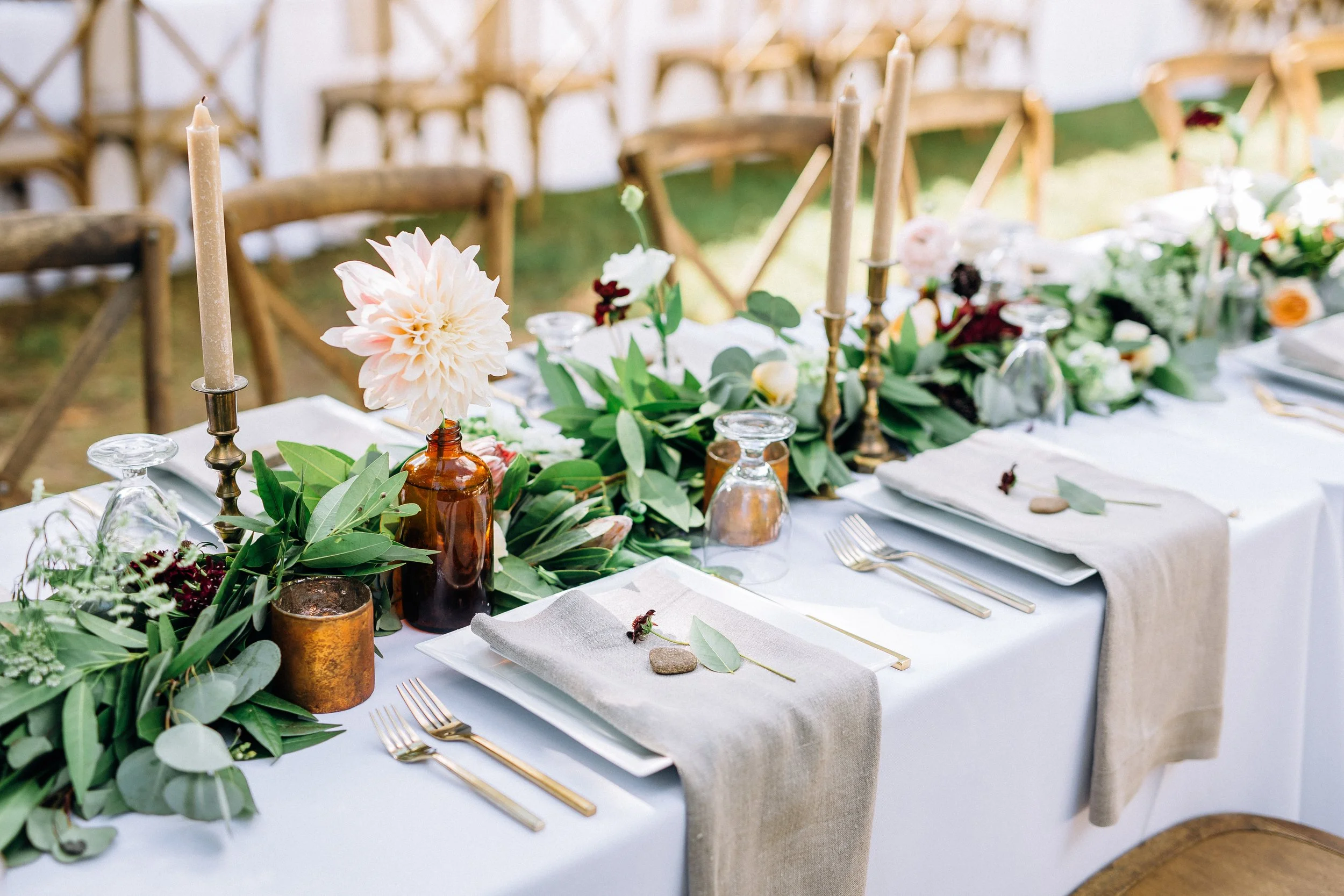 Elegant outdoor dining table decorated with greenery, flowers, candles, and tableware, set for a special occasion. Reception Setup Wedding photography by Sowing Clover Photography. Nashville TN
