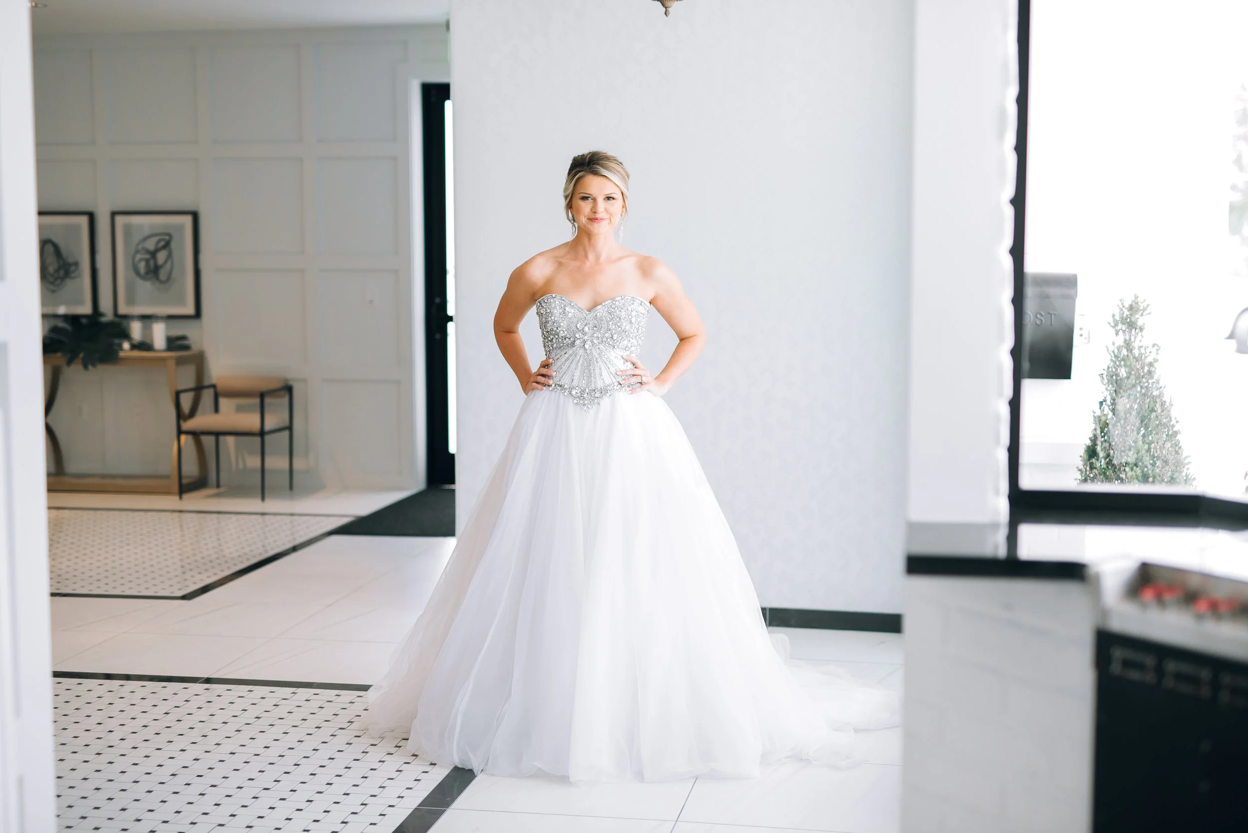 A woman in a wedding dress standing indoors with hands on hips, smiling at Clay Theater, Green Cover Spings, Florida. Wedding Photography by Sowing Clover Photography.