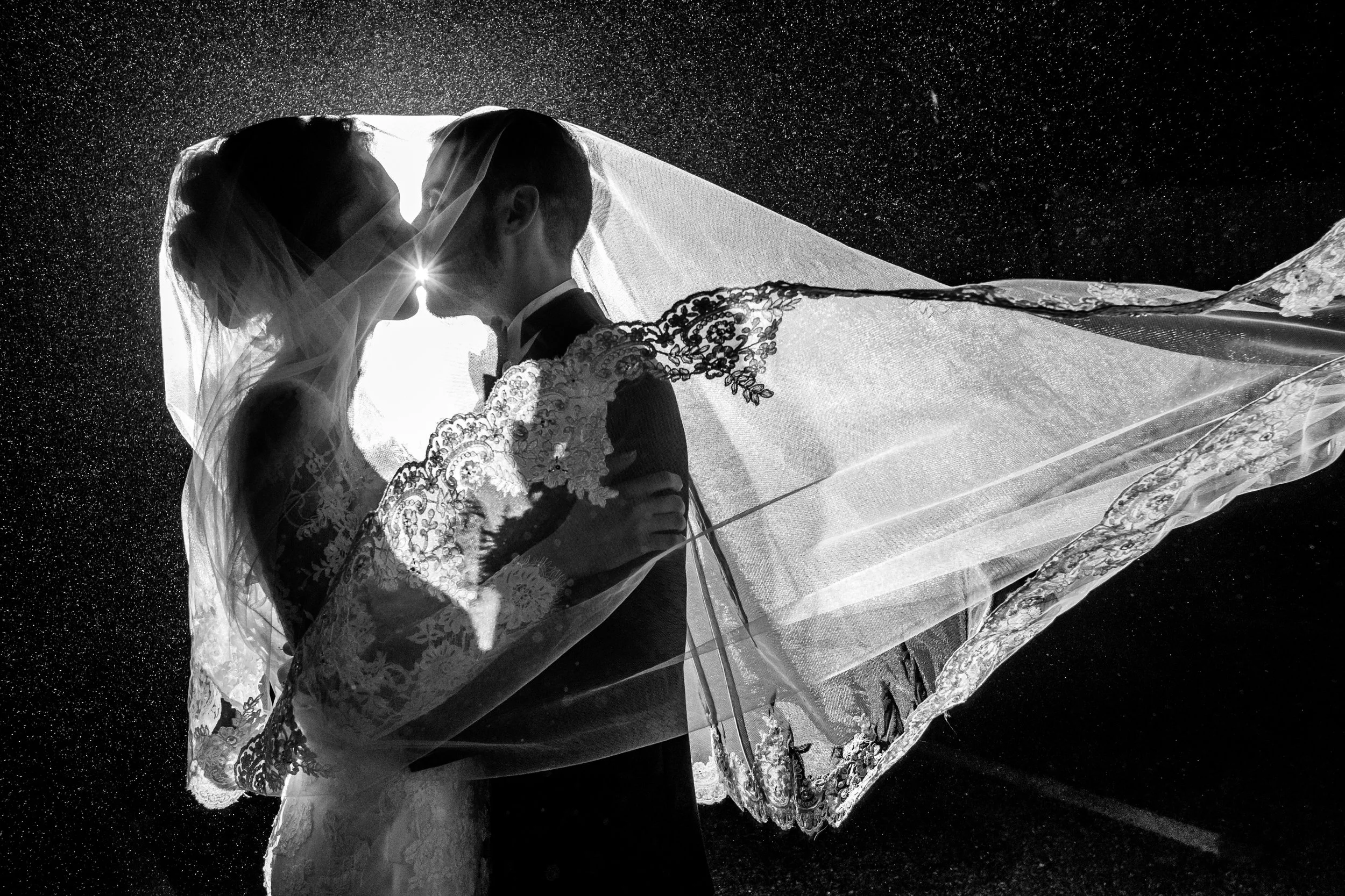 Silhouette of a newlywed couple kissing behind a wedding veil against a dark background with water droplets Wedding Photography in Nashville by Sowing Clover Photography.
