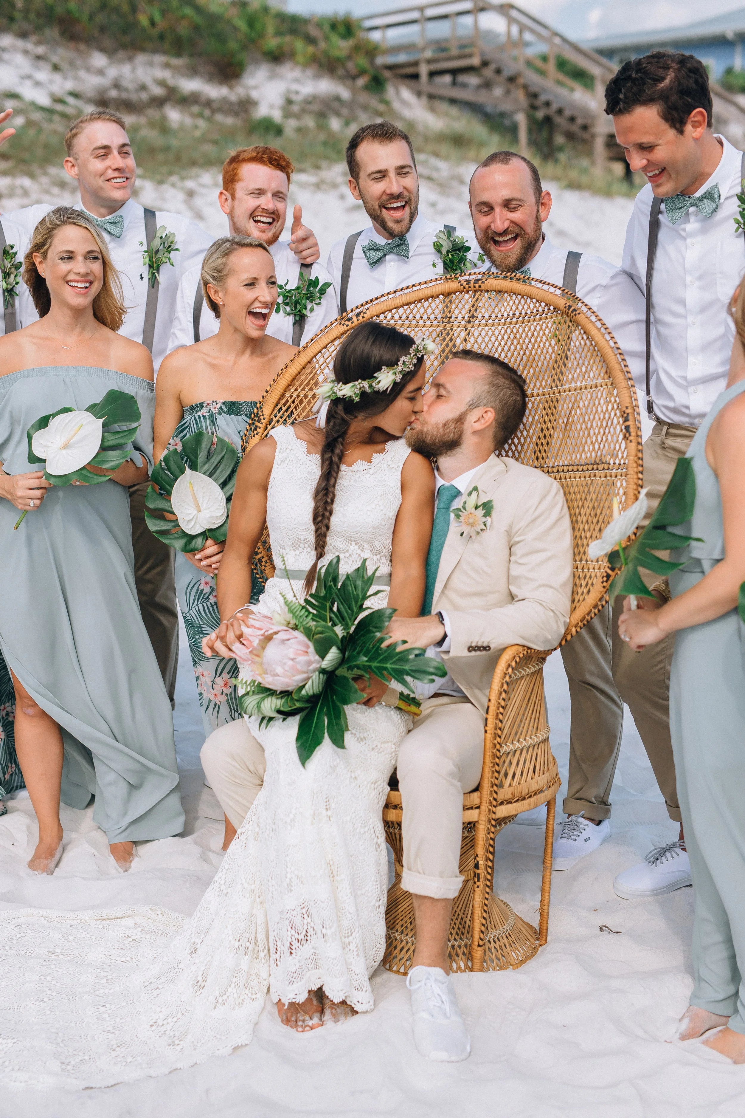 A wedding on the beach with a bride and groom sharing a kiss surrounded by their bridal party. Florida beach wedding at a private residence. Wedding photography by Sowing Clover Photography.