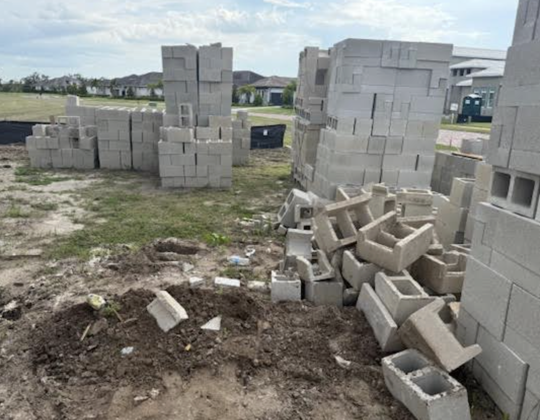 Stacks of concrete blocks at a construction site with an ongoing building project in a suburban neighborhood.
