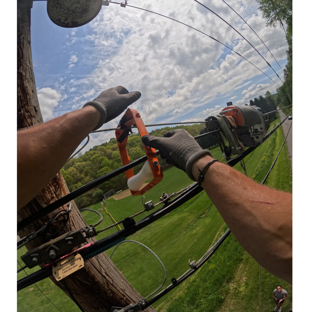 A bonding clamp connecting an aerial fiber messenger strand to a vertical pole ground wire on a joint-use utility pole