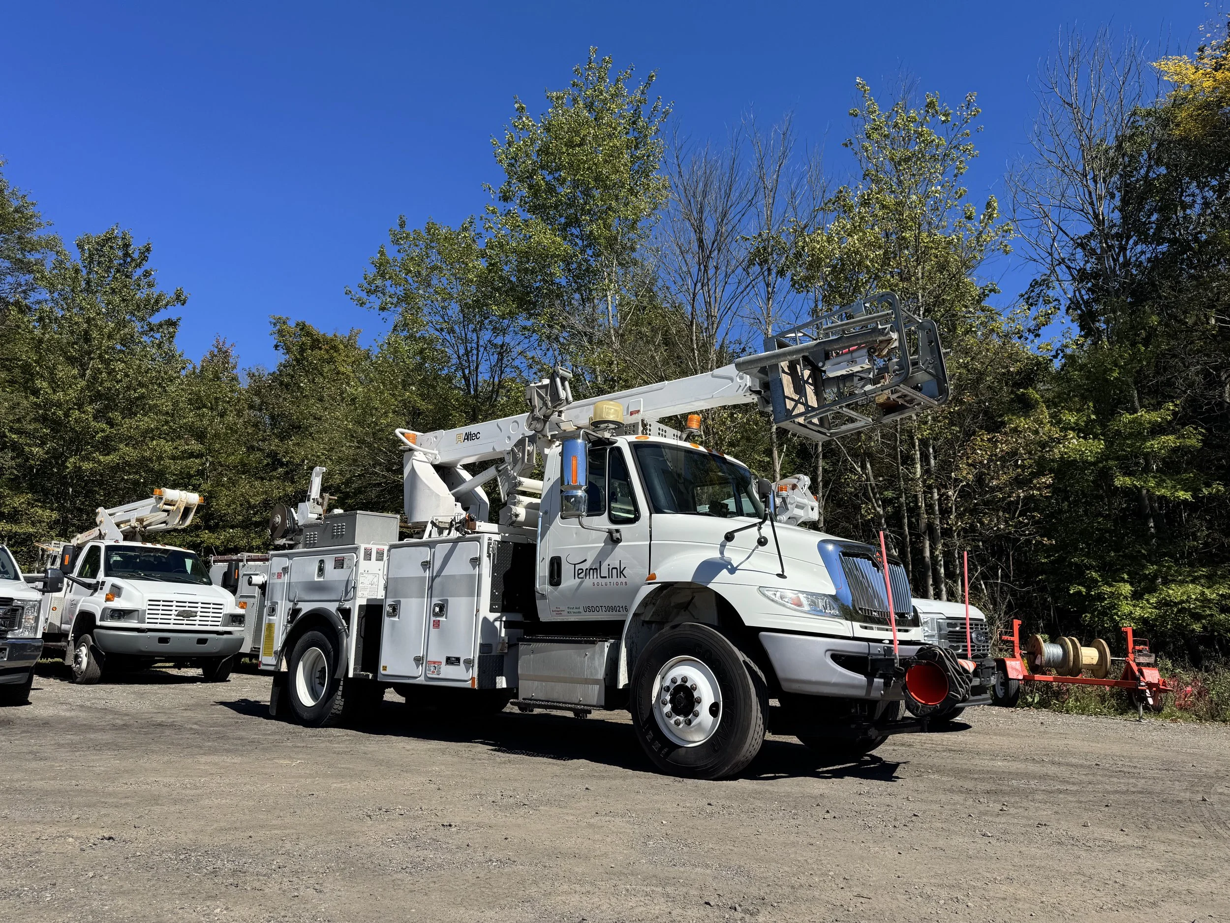 TermLink Solutions bucket truck set up safely with outriggers on pads beside an aerial fiber span
