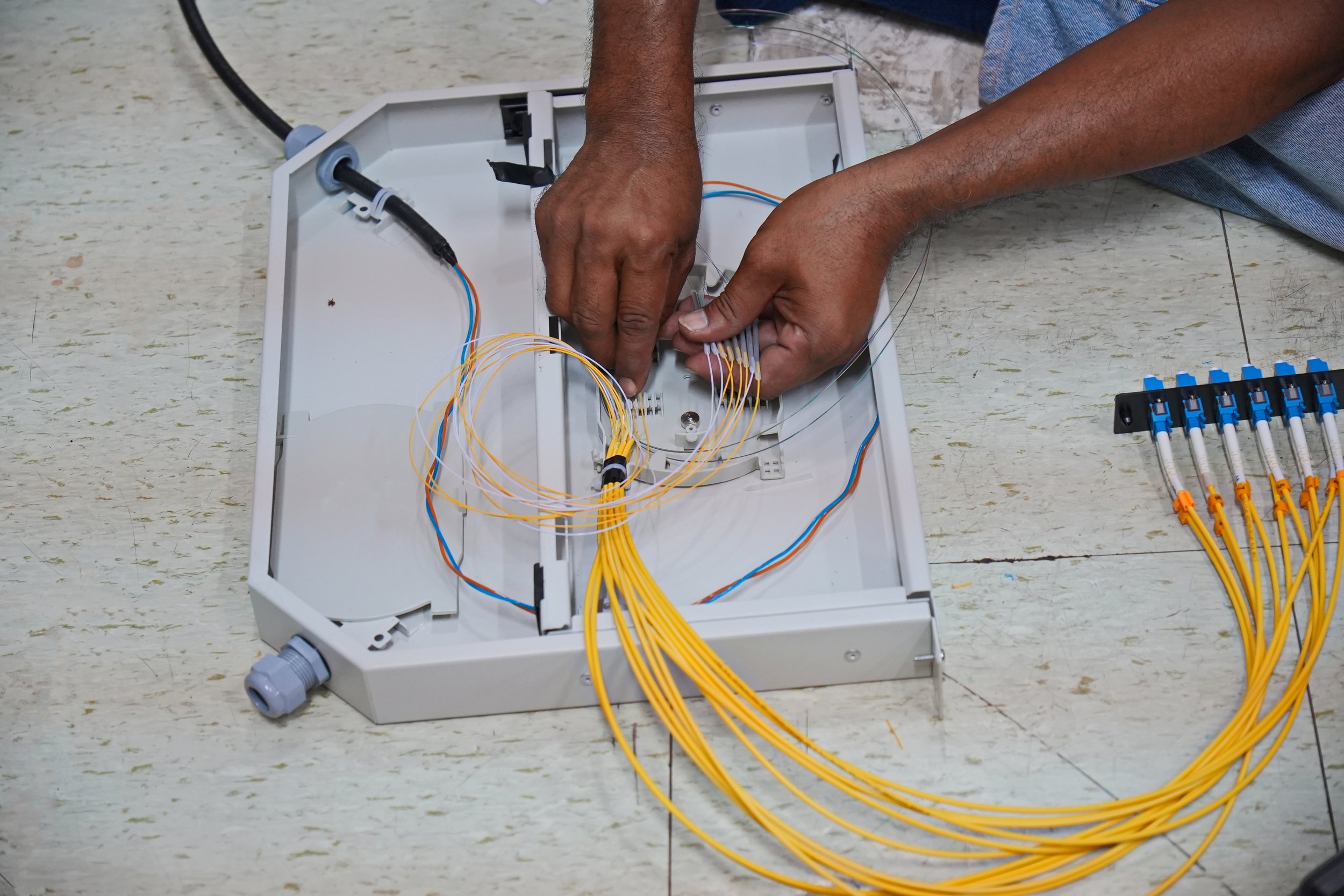 Fiber optic technician performing precision splice work on fiber cables