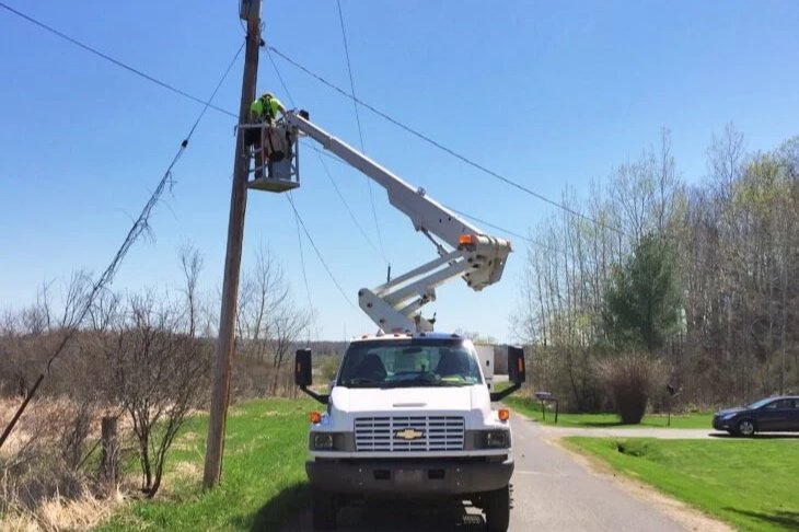 Fiber optic technician installing aerial cable from bucket truck during prime spring construction season