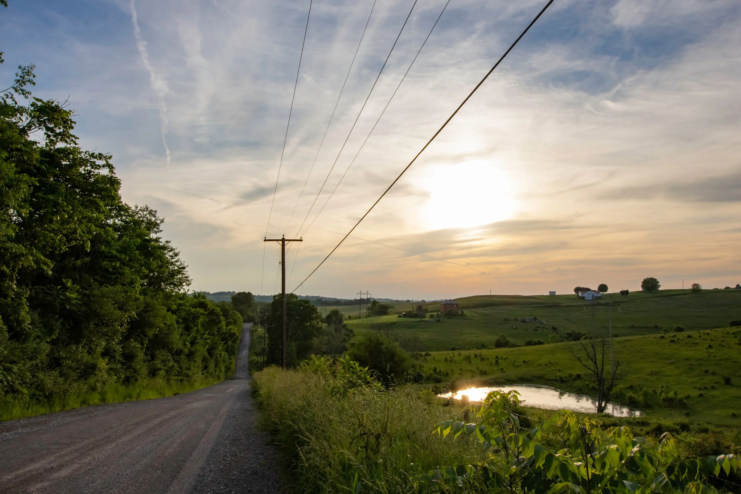Public road right-of-way with utility poles carrying telecommunications and power infrastructure along the corridor.