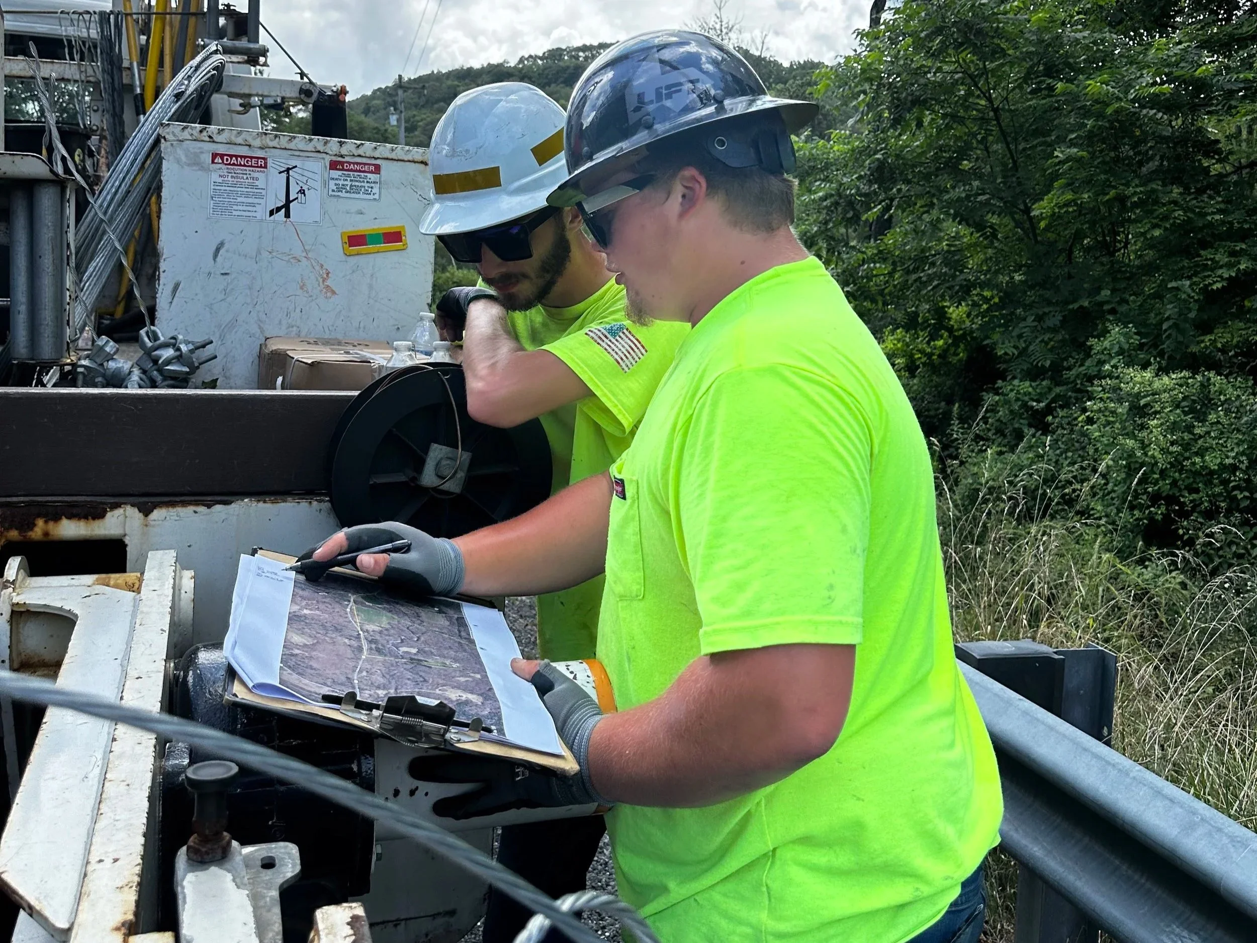 crew member reviewing prints or a route map on the tailgate