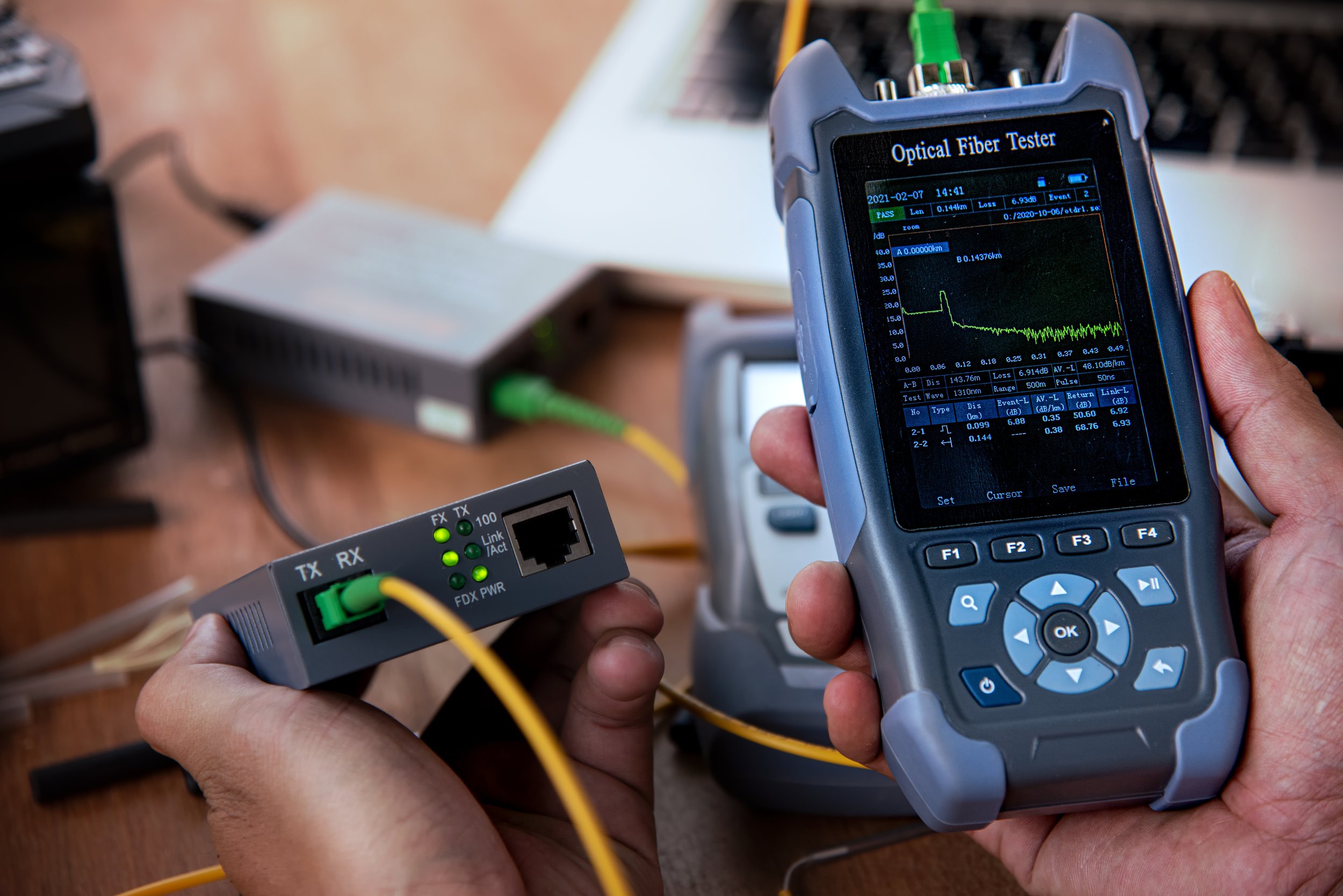 Technician performing OTDR testing on a fiber optic link to measure insertion loss and locate faults against the calculated loss budget.