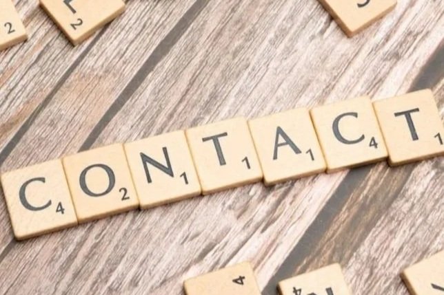 Scrabble tiles spelling the word 'CONTACT' on a wooden table.