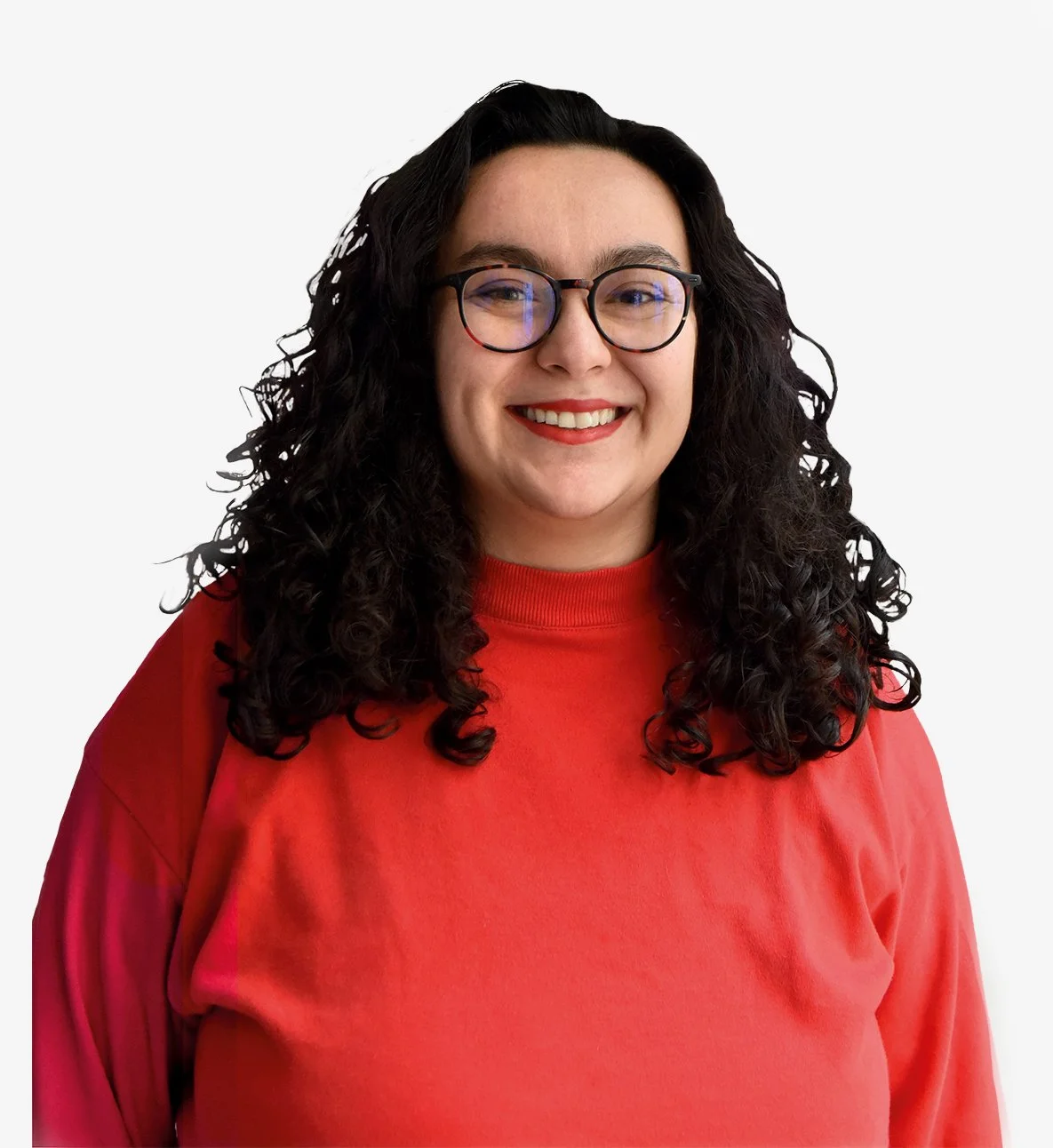 Photo d'une femme de face, qui souri à pleines dents. Elle a les cheveux bouclés, noirs et longs un peu plus bas que les épaules. Elle porte un haut col roulé rouge vif et du rouge à lèvre rouge. Elle porte des lunettes. 
