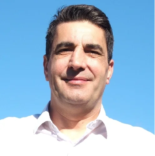 Portrait d'un homme souriant avec un fond de ciel bleu.