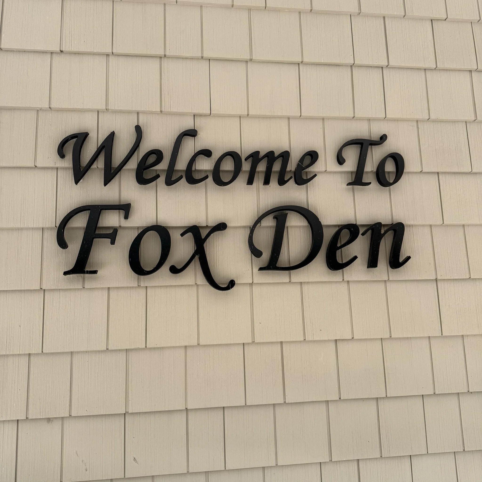 Black cursive text on a beige wall reads "Welcome to Fox Den".
