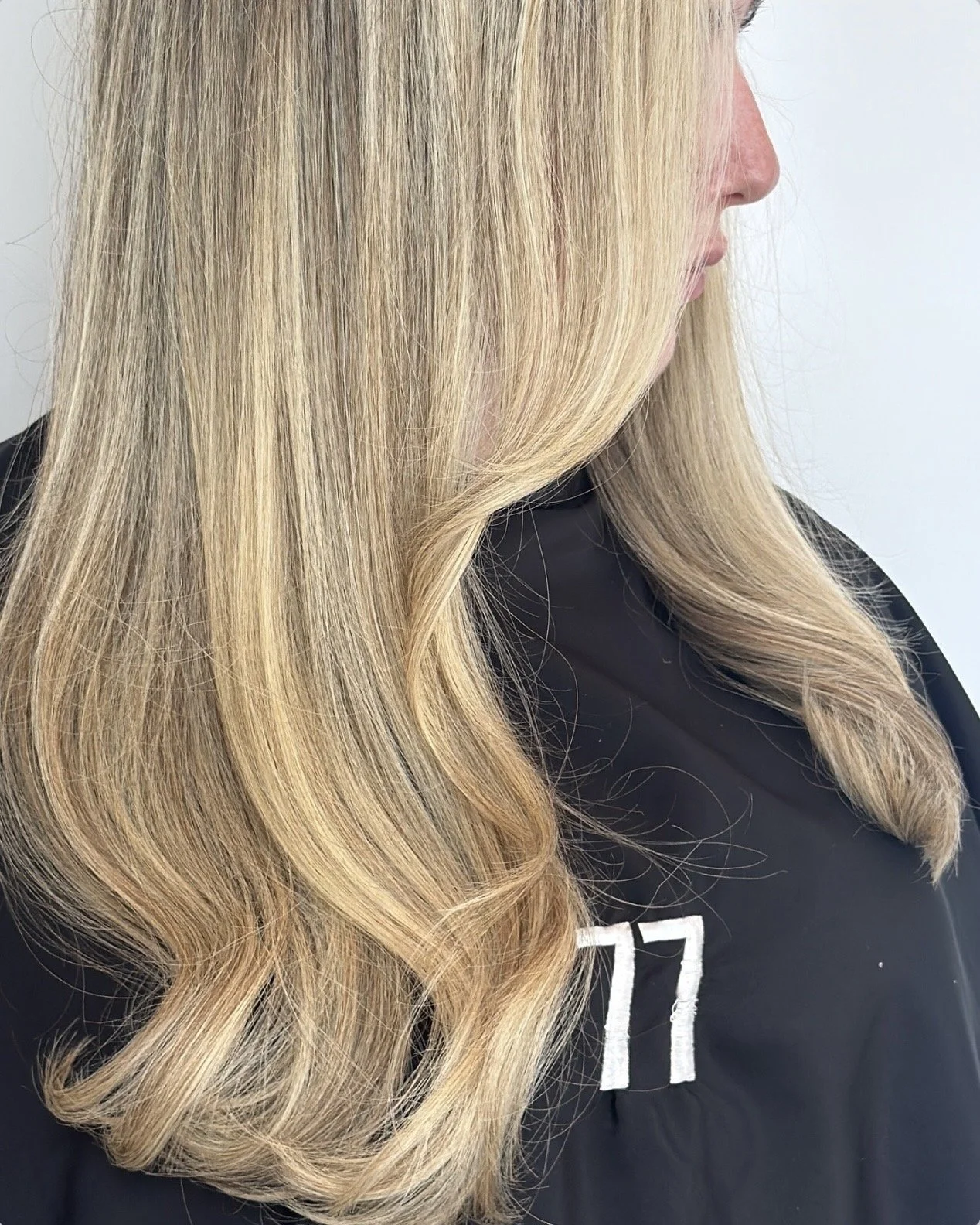 Close-up of a woman with long, wavy blonde hair wearing a black sweatshirt.