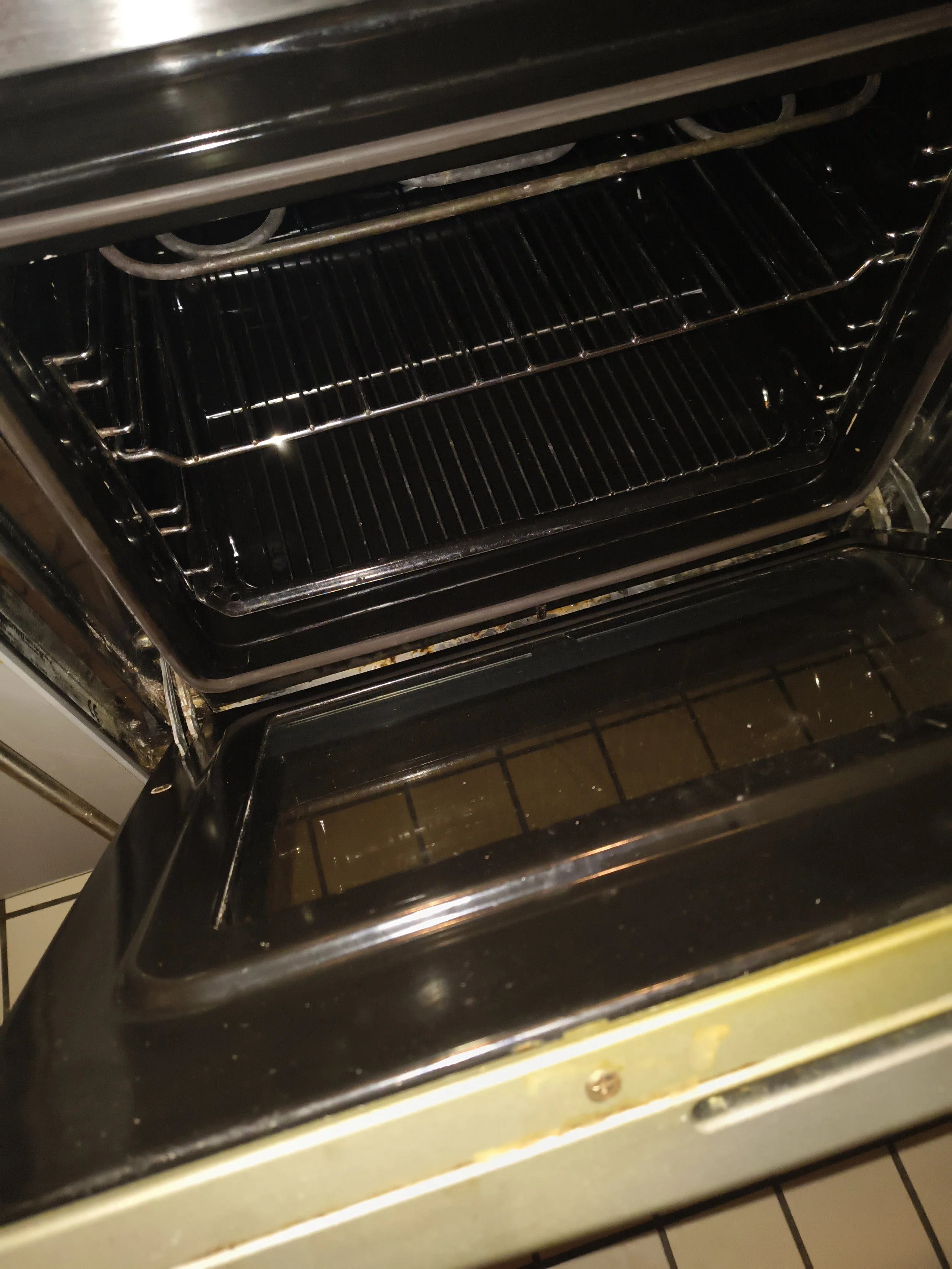 Inside open kitchen oven with two empty baking racks and glass window on the oven door.