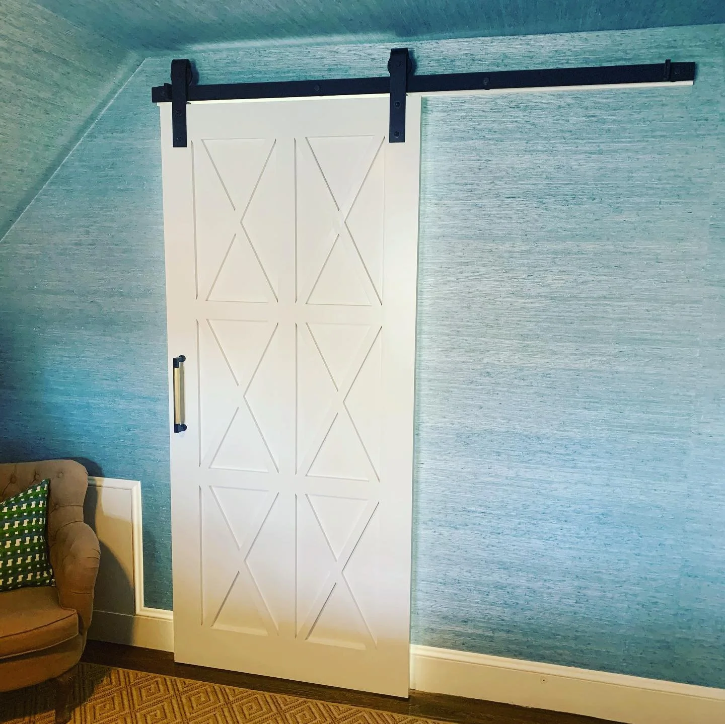 White sliding barn door with geometric patterns on a blue textured wall.