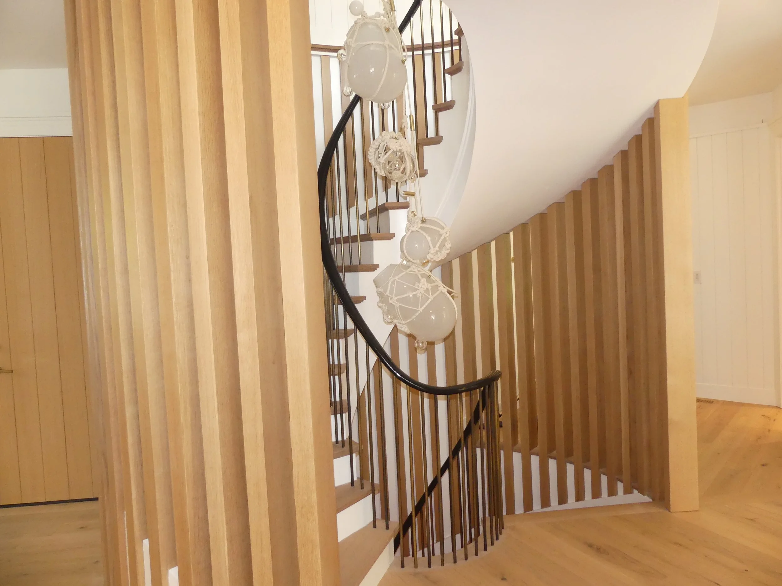Interior view of a wooden staircase with hanging white decorative lamps, surrounded by wooden paneling on the walls.
