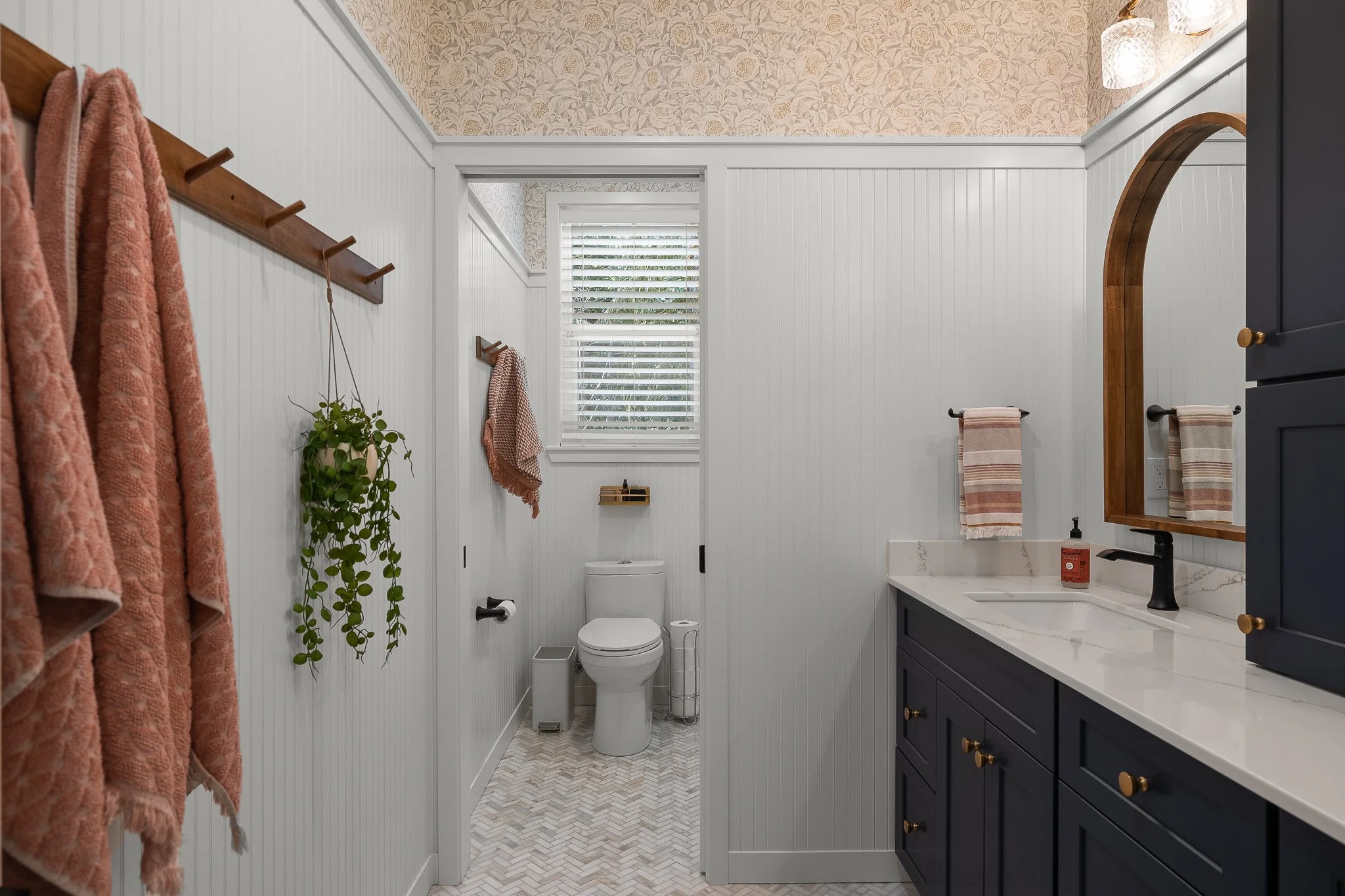 Bathroom with navy blue vanity, white countertop, framed mirror, towels, and natural light from window