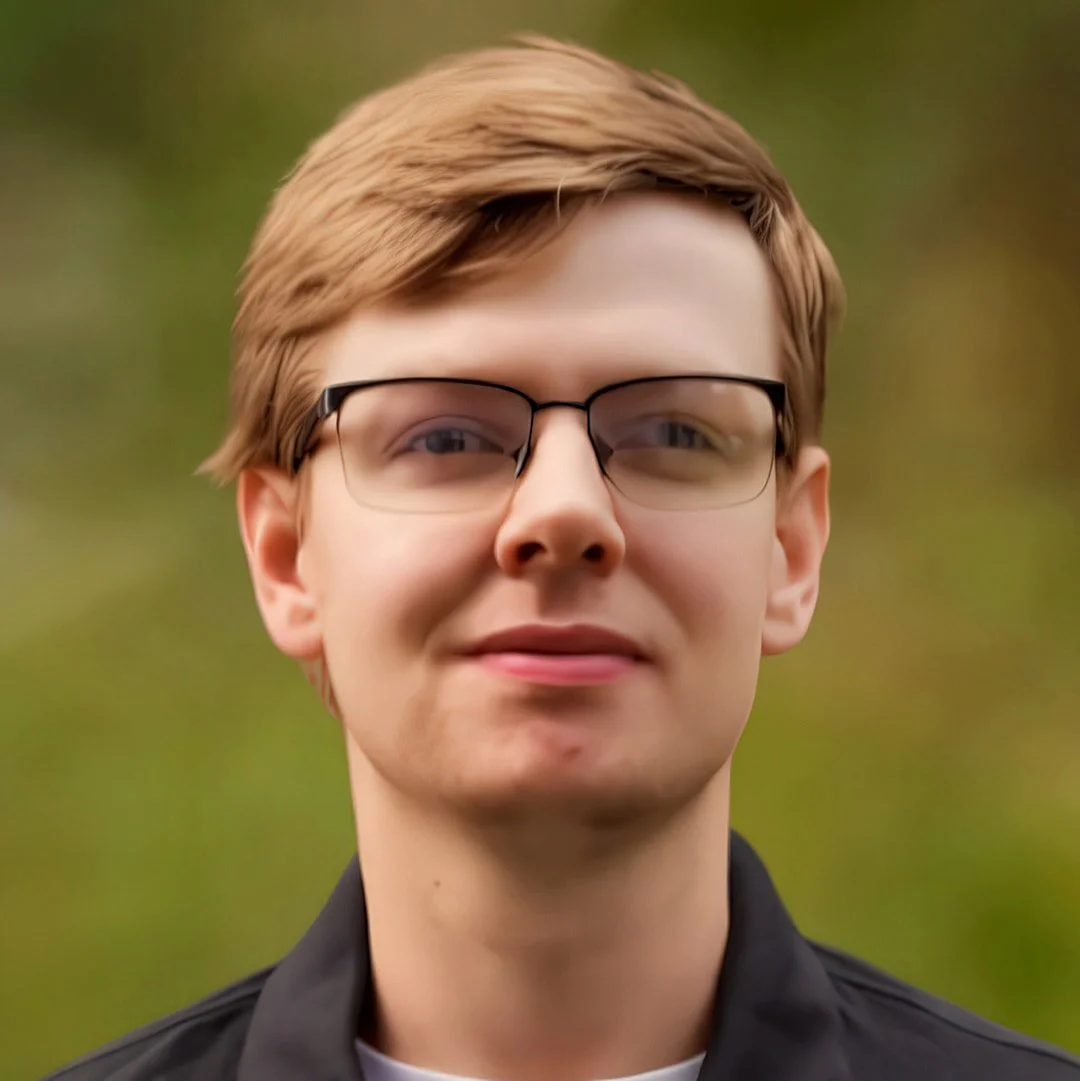 Young man with light brown hair, glasses, and fair skin outdoors with a blurred green background.