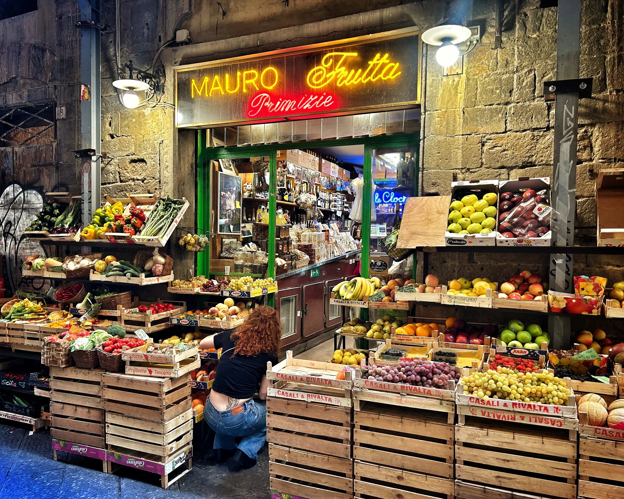 A street market storefront in Florence, Italy with fresh fruits and vegetables.