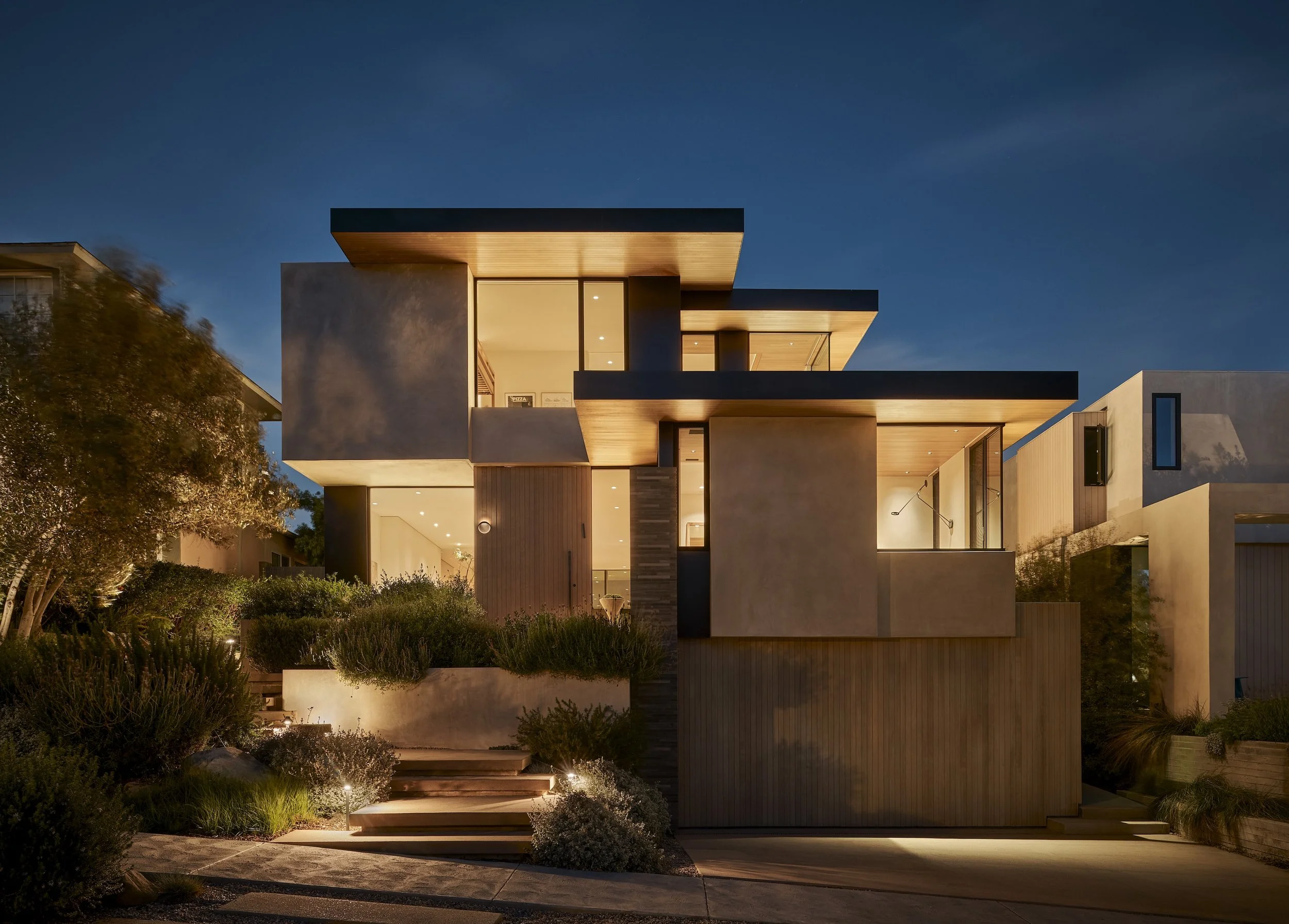 Luxury Westwood residence illuminated at dusk with contemporary architecture and custom landscape lighting, remodeled by JBurton General Contractor in Westwood, Los Angeles.