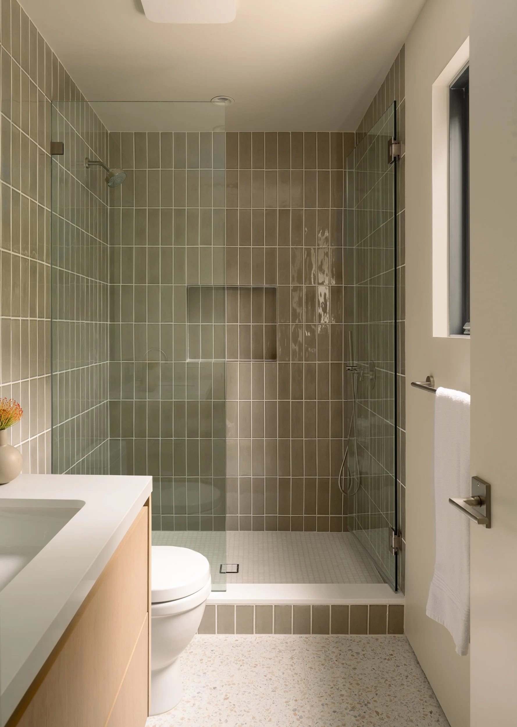 Contemporary walk-in shower with floor-to-ceiling tile, frameless glass enclosure, and custom niche, remodeled by JBurton General Contractor in Beverly Crest, Los Angeles.