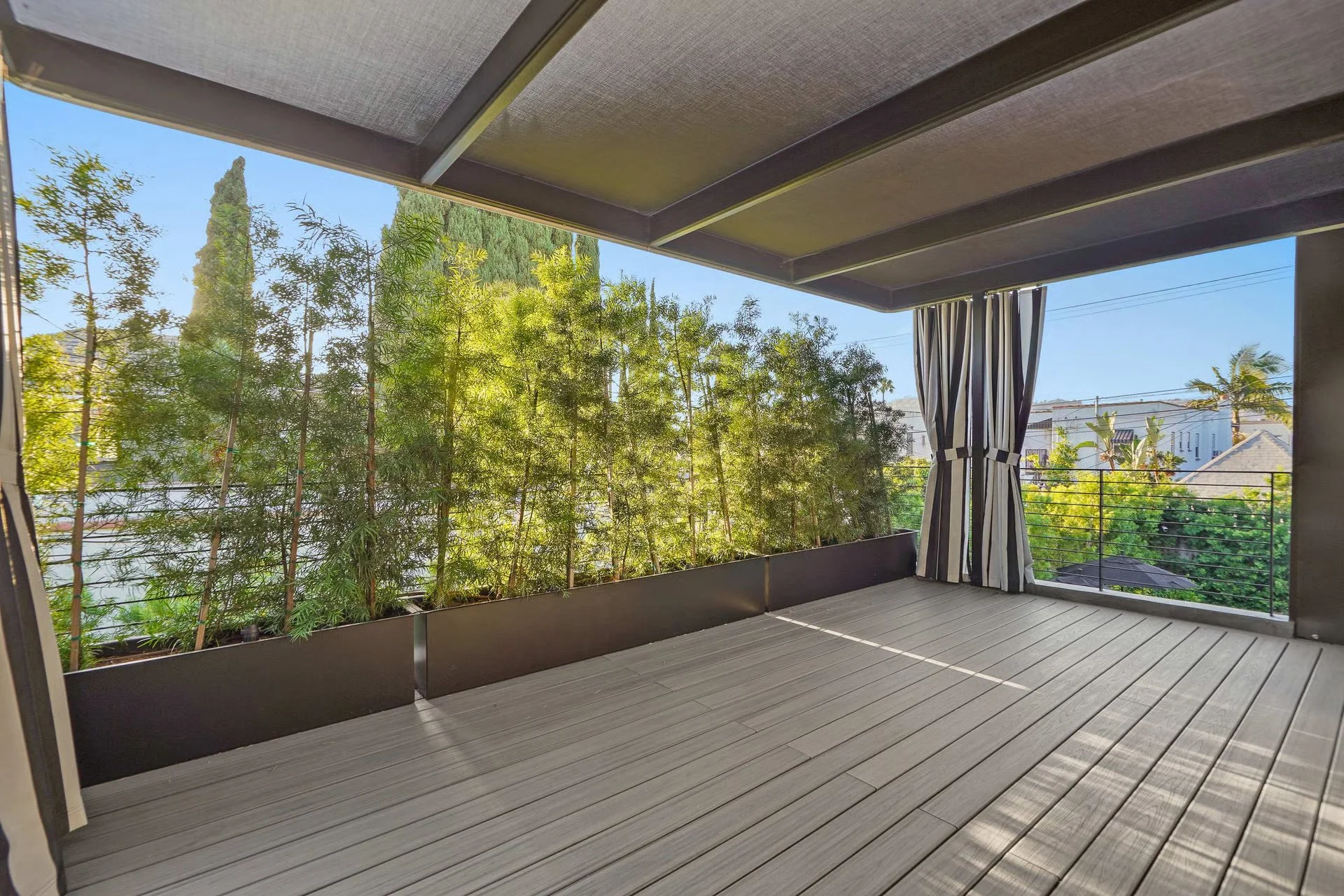 Covered outdoor lounge featuring warm wood decking, retractable shade panels, and a seamless transition to the landscaped backyard, remodeled by JBurton General Contractor.