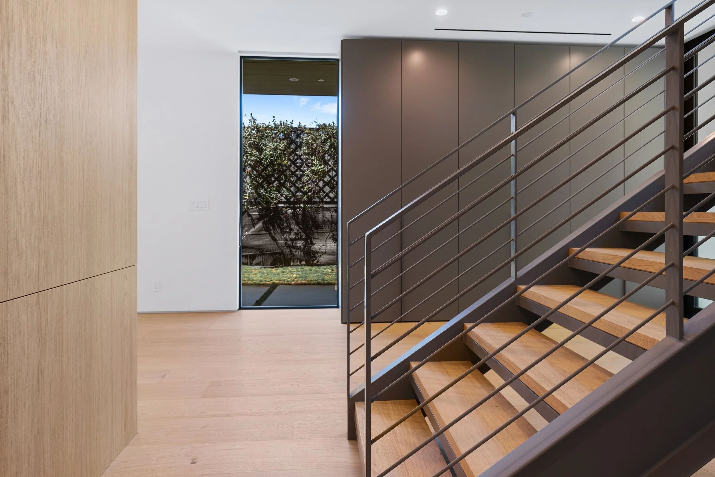 Open stair hall showcasing handcrafted oak treads, contemporary steel railings, and precision finish carpentry by JBurton General Contractor.