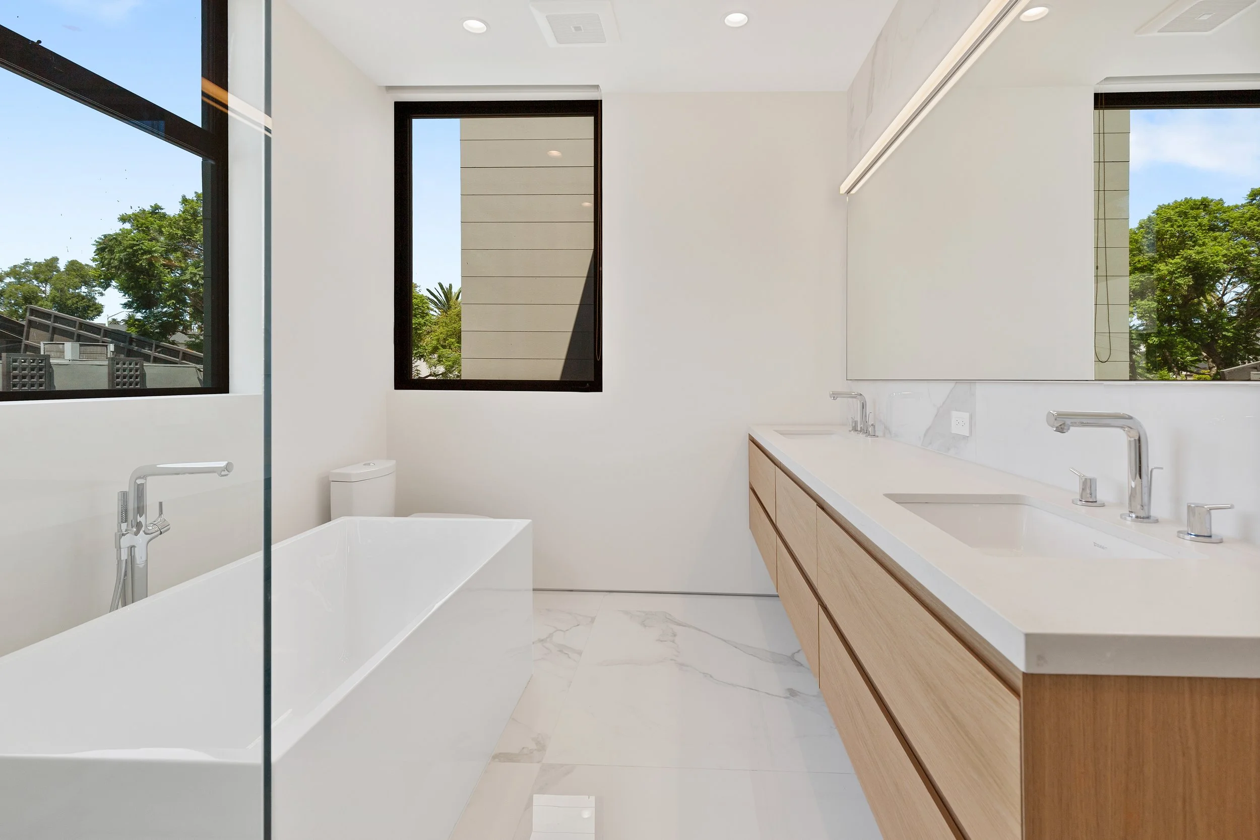 Spa-inspired primary bathroom featuring a floating vanity, freestanding soaking tub, oversized walk-in shower, and elegant marble finishes by JBurton General Contractor.