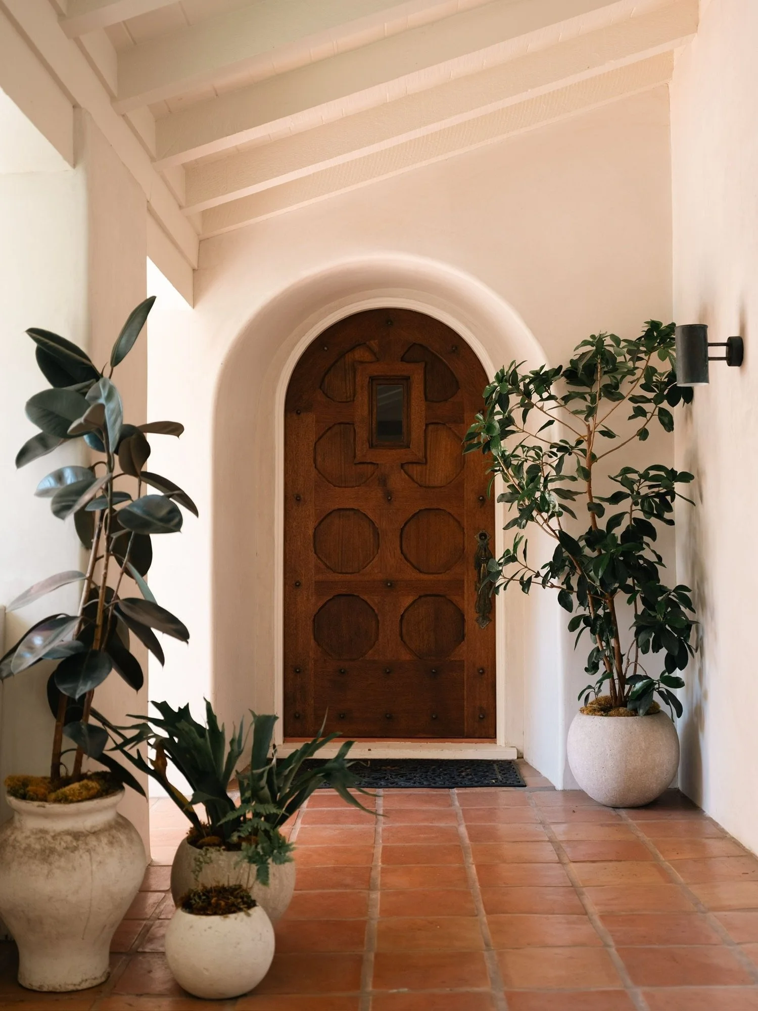 Restored Spanish Revival front entry featuring a handcrafted wood door and traditional arched opening.