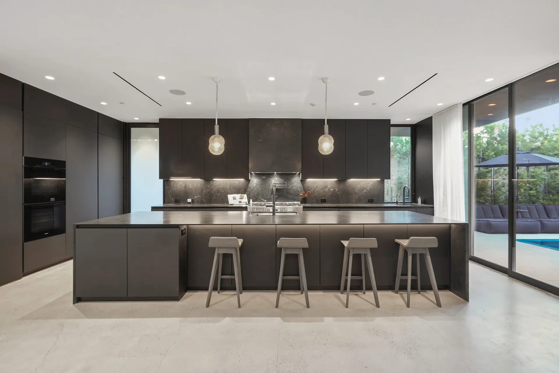 Luxury kitchen with custom dark cabinetry, waterfall island, and designer pendant lighting, remodeled by JBurton General Contractor in Beverly Grove, Los Angeles.