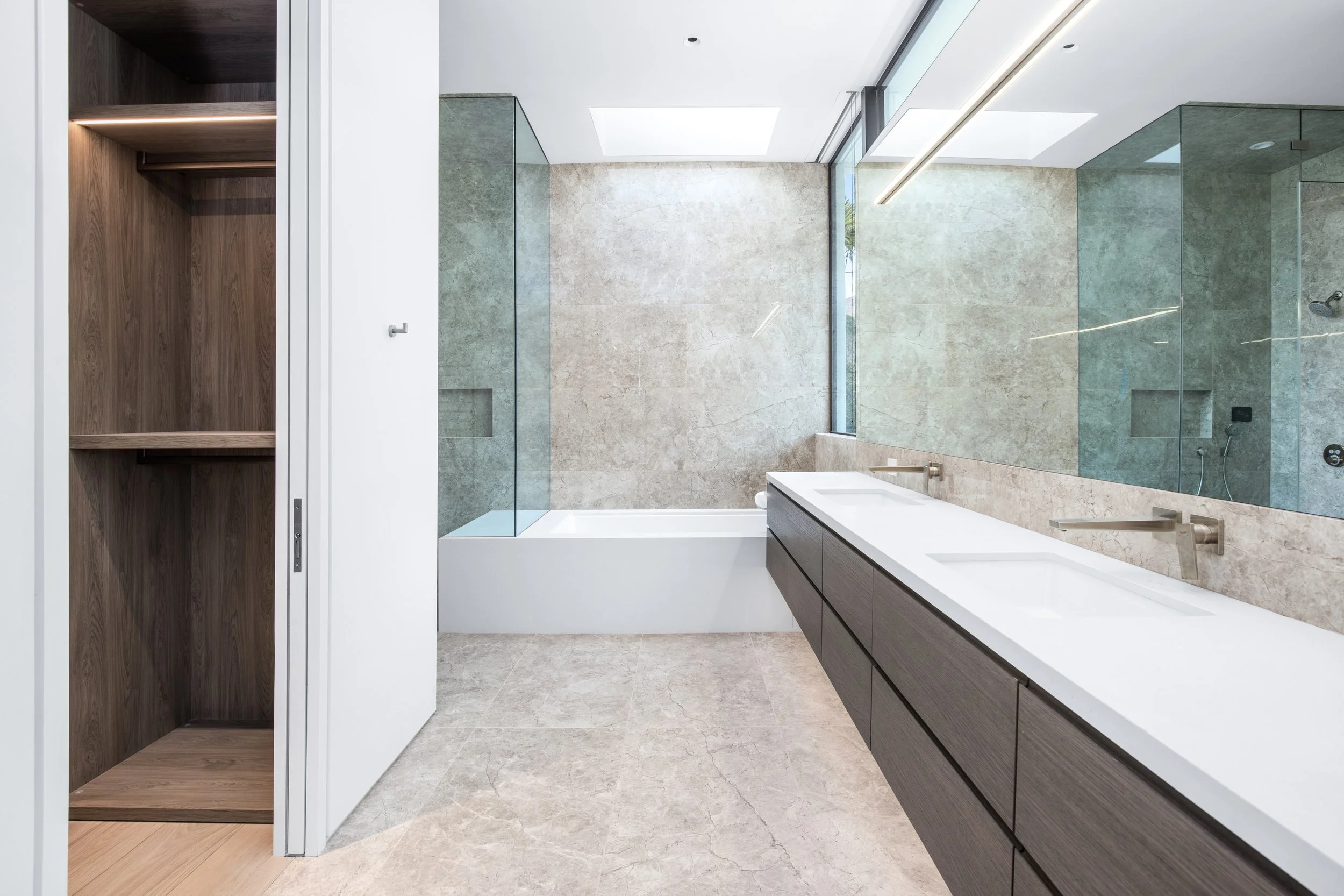 Spacious spa bathroom with soaking tub, floating vanity, and natural stone surfaces crafted by JBurton General Contractor.
