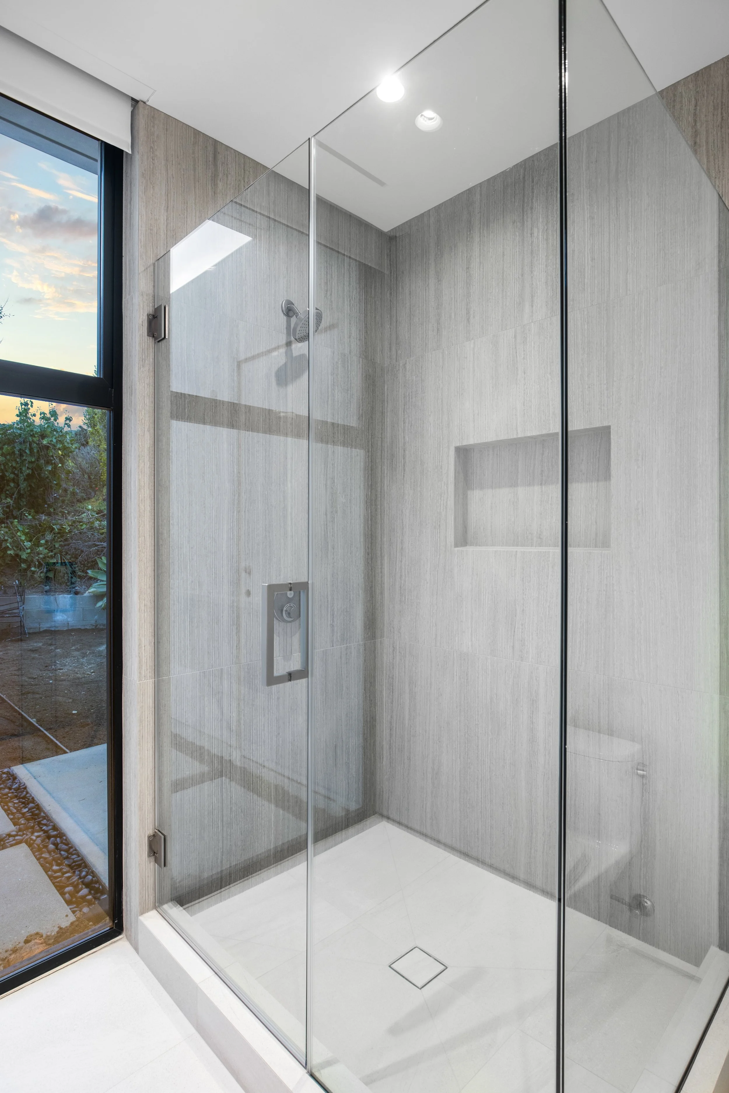 Luxury walk-in shower featuring full-height porcelain slab walls, recessed storage niche, and precision waterproof detailing by JBurton General Contractor.