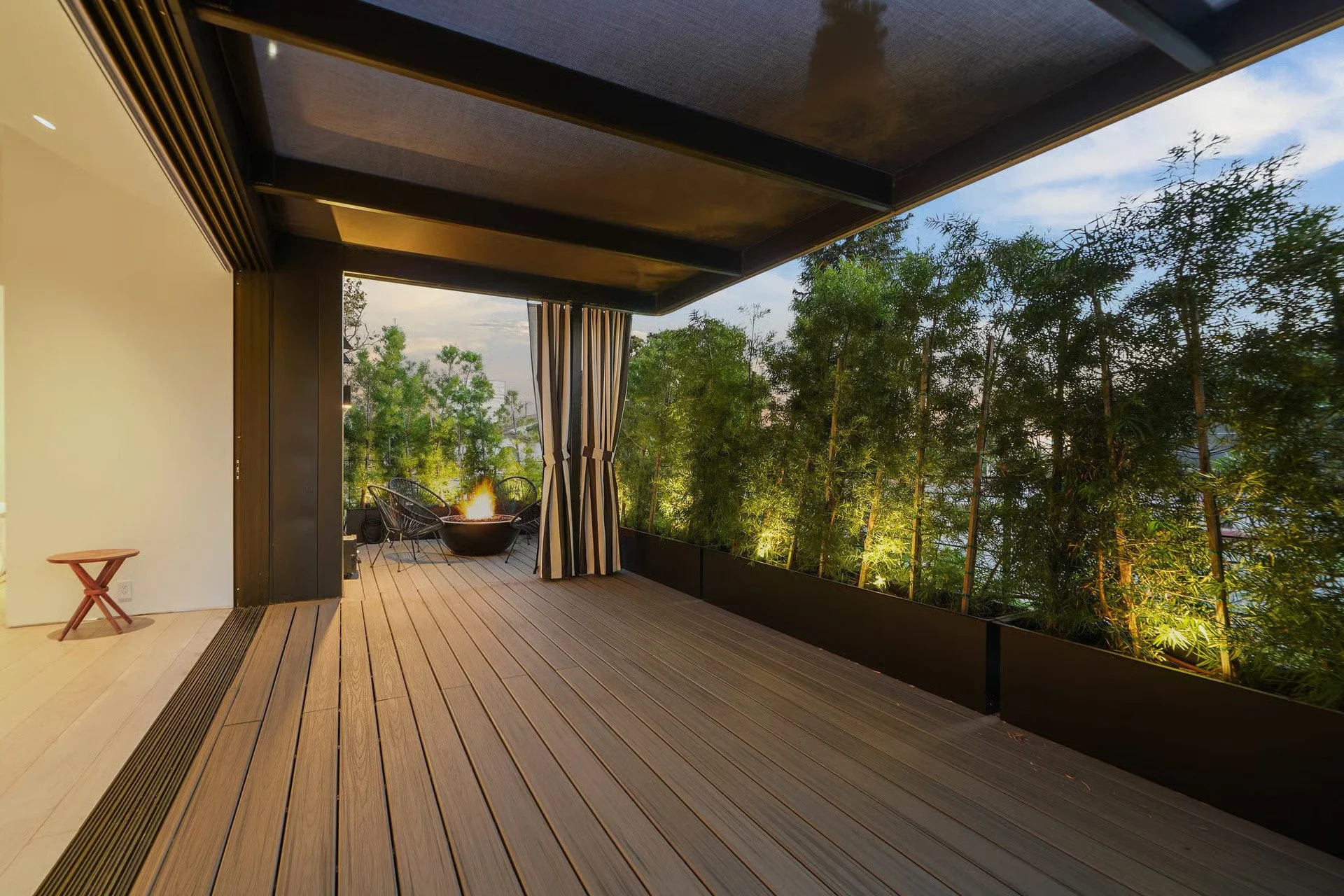 Covered outdoor lounge featuring warm wood decking, retractable shade panels, and a seamless transition to the landscaped backyard, remodeled by JBurton General Contractor.