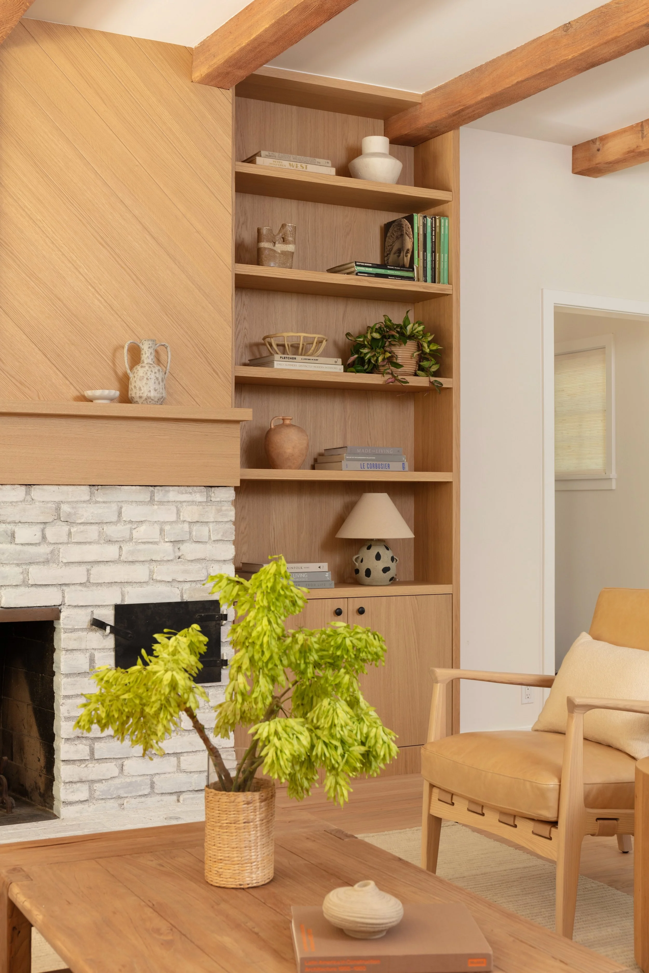Living room featuring custom white oak millwork, built-in shelving, and a painted brick fireplace, completed by JBurton General Contractor as part of a whole-home remodel in Brentwood, Los Angeles