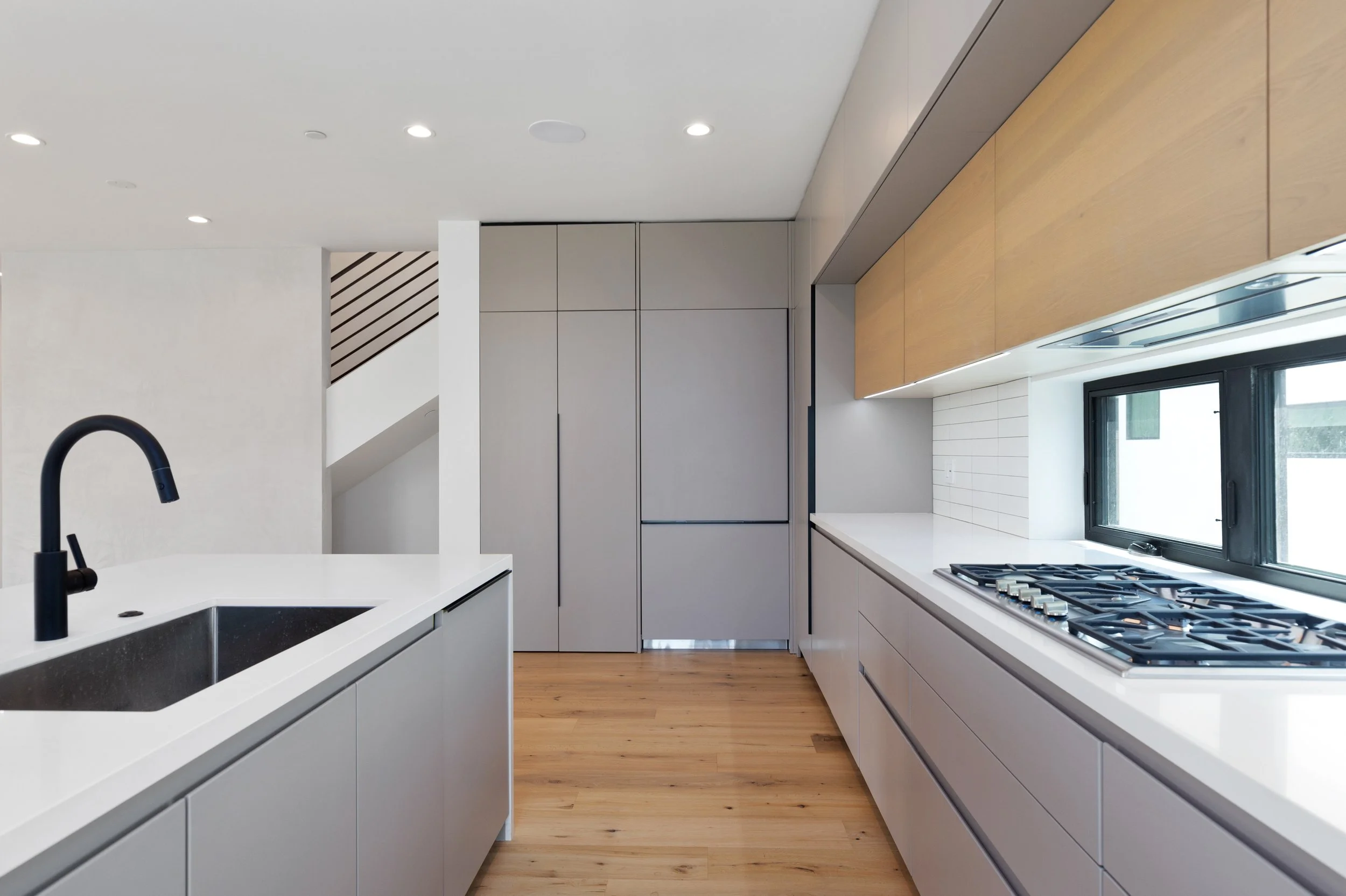 Contemporary galley kitchen in a Faircrest Heights townhome with full-height custom cabinetry, quartz countertops, and wide-plank oak flooring.