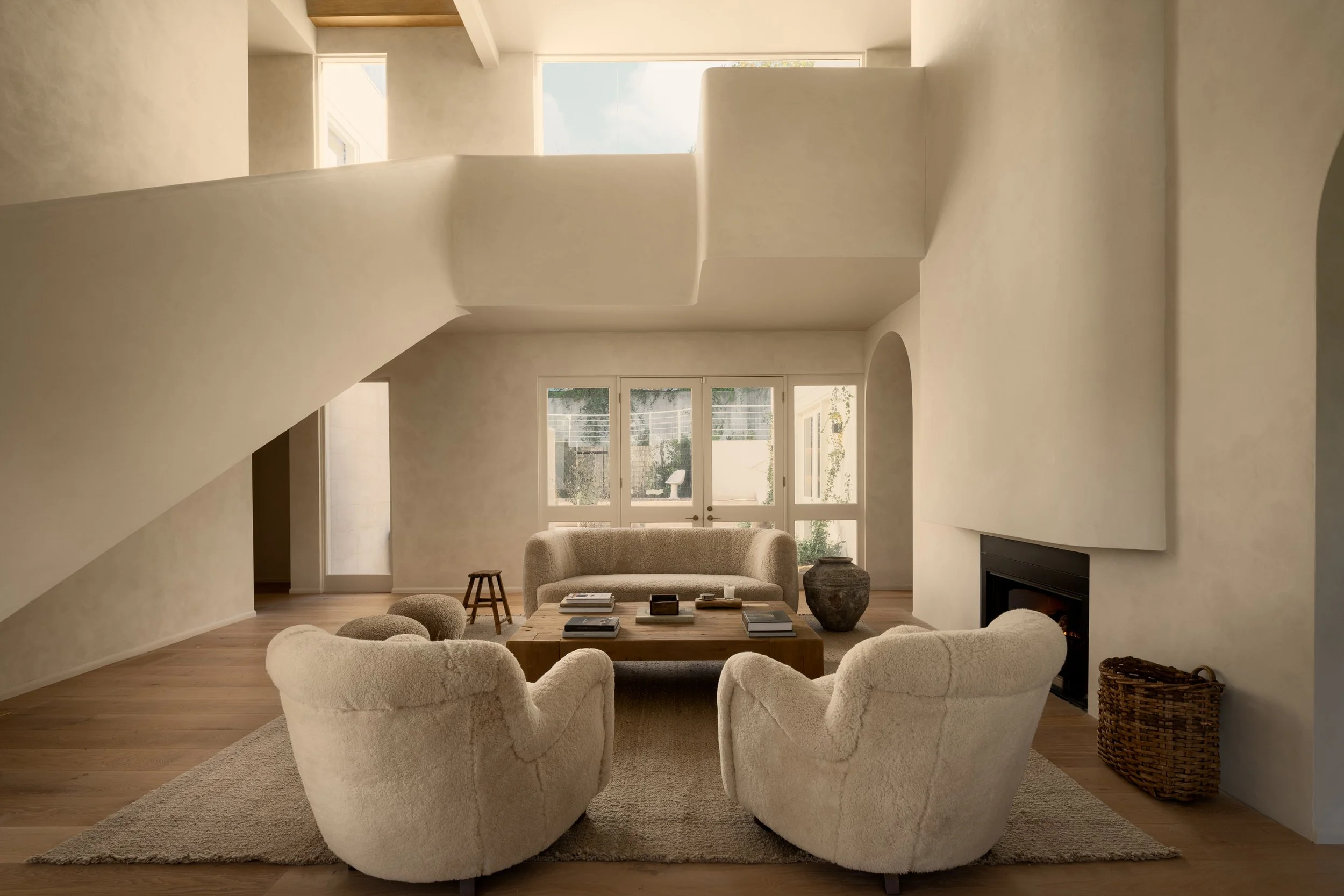 Double-height living room with sculptural floating staircase, vaulted ceilings, and warm contemporary interiors, completed by JBurton General Contractor for a luxury home remodel in Benedict Canyon, Los Angeles.