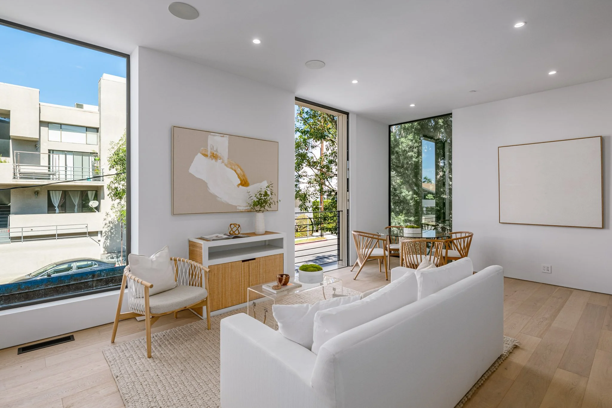 Bright open living and dining space filled with natural light, oversized corner windows, and contemporary finishes by JBurton General Contractor.