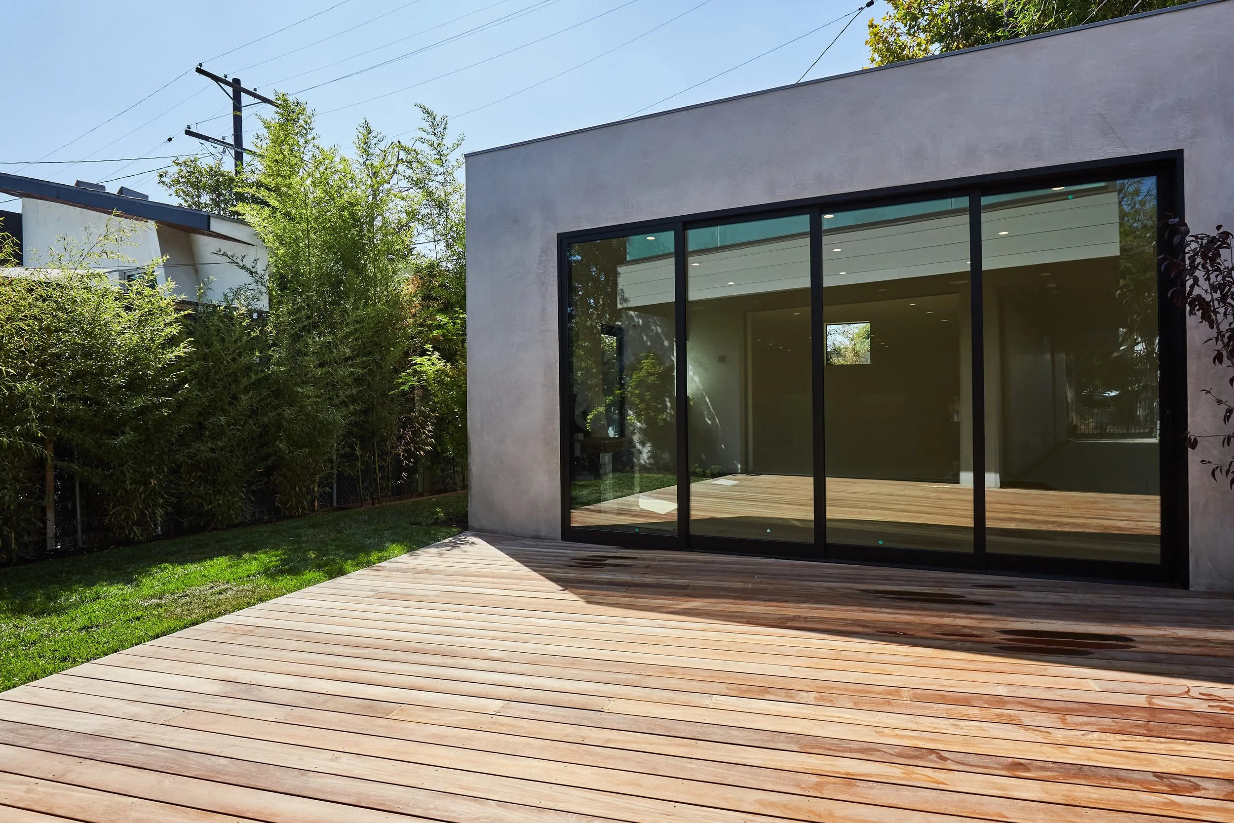 Rear exterior featuring expansive sliding glass doors opening onto a spacious wood deck, creating seamless California indoor-outdoor living by JBurton General Contractor.
