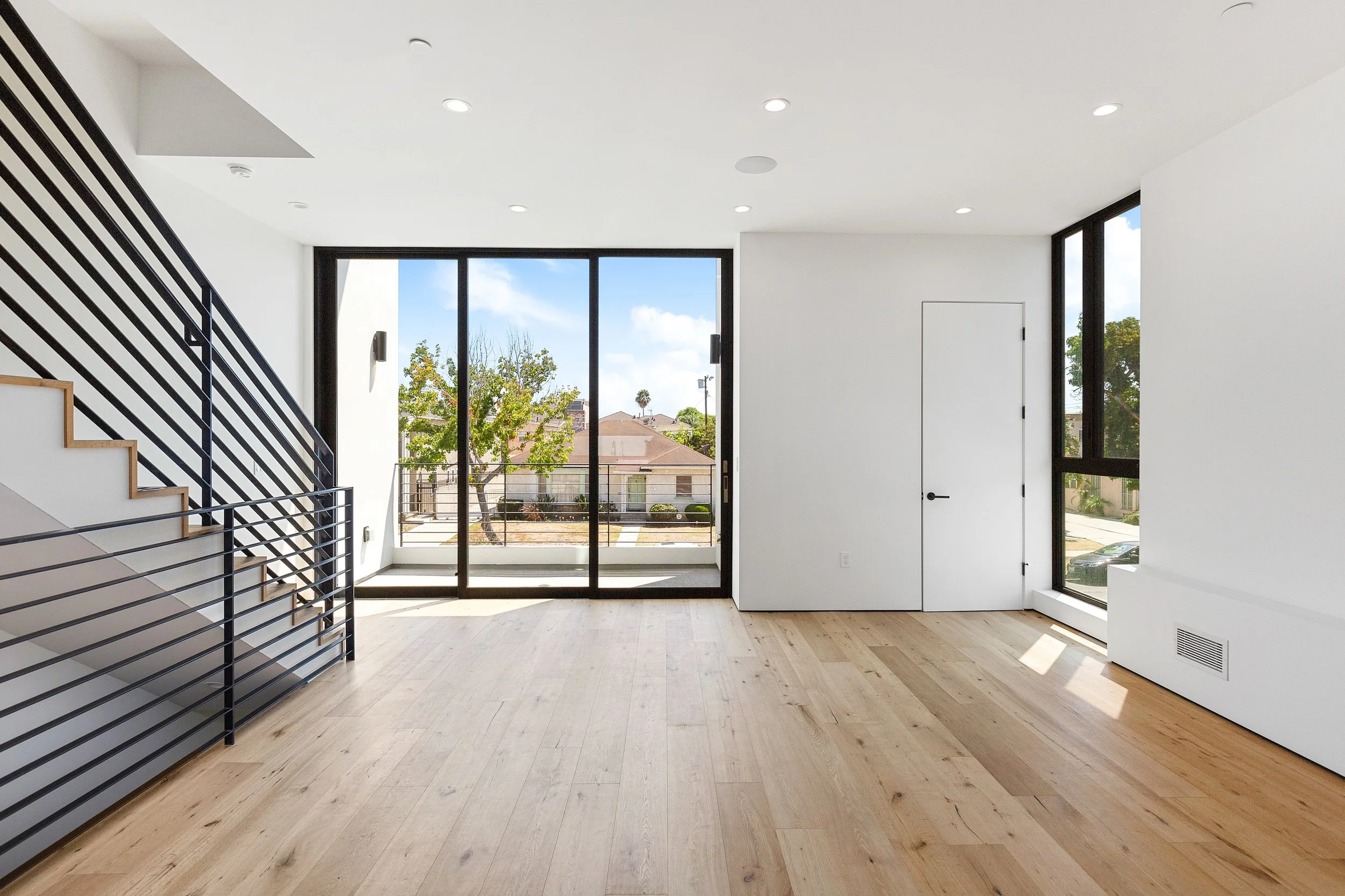 Bright open-concept living room with wide-plank oak flooring and large sliding glass doors, completed by JBurton General Contractor for a Faircrest Heights townhome.