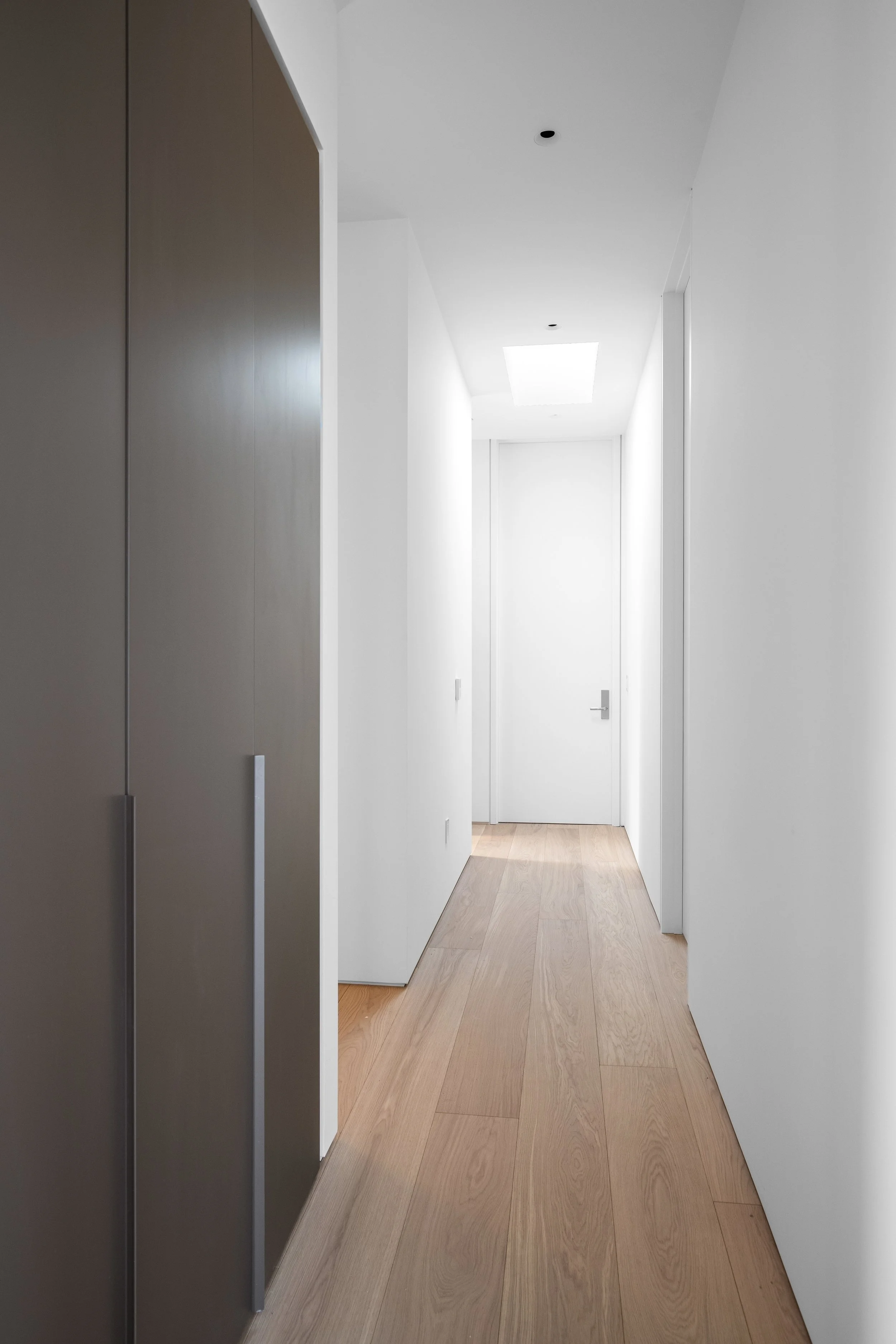 Architectural gallery hallway featuring minimalist detailing, flush doors, and precision finish carpentry in a custom Malibu residence built by JBurton General Contractor.