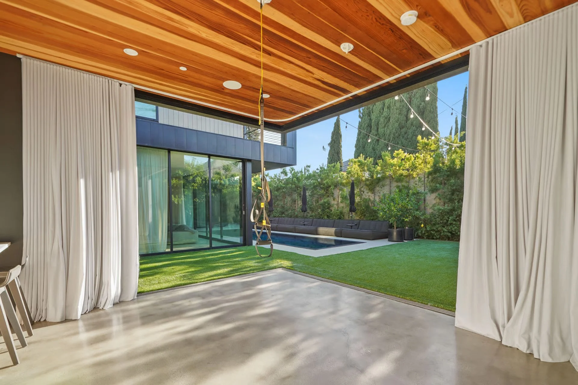 Covered patio with custom cedar ceiling overlooking the landscaped backyard and pool, remodeled by JBurton General Contractor in Beverly Grove, Los Angeles.