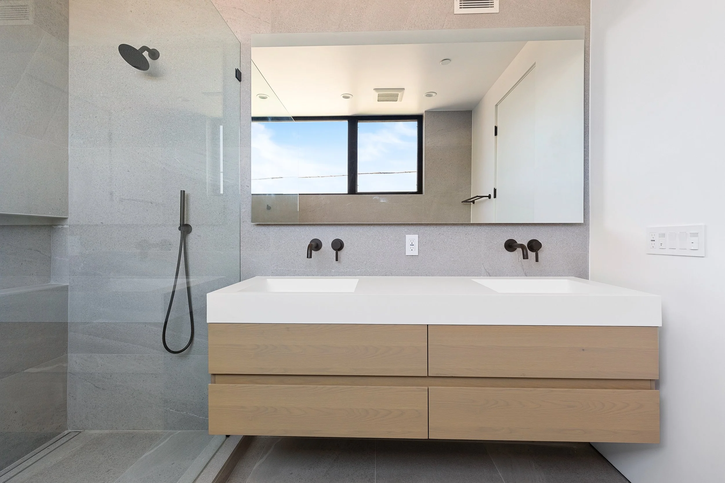 Primary bathroom in a Faircrest Heights townhome featuring a floating double vanity, quartz countertop, frameless glass shower, and contemporary finishes.