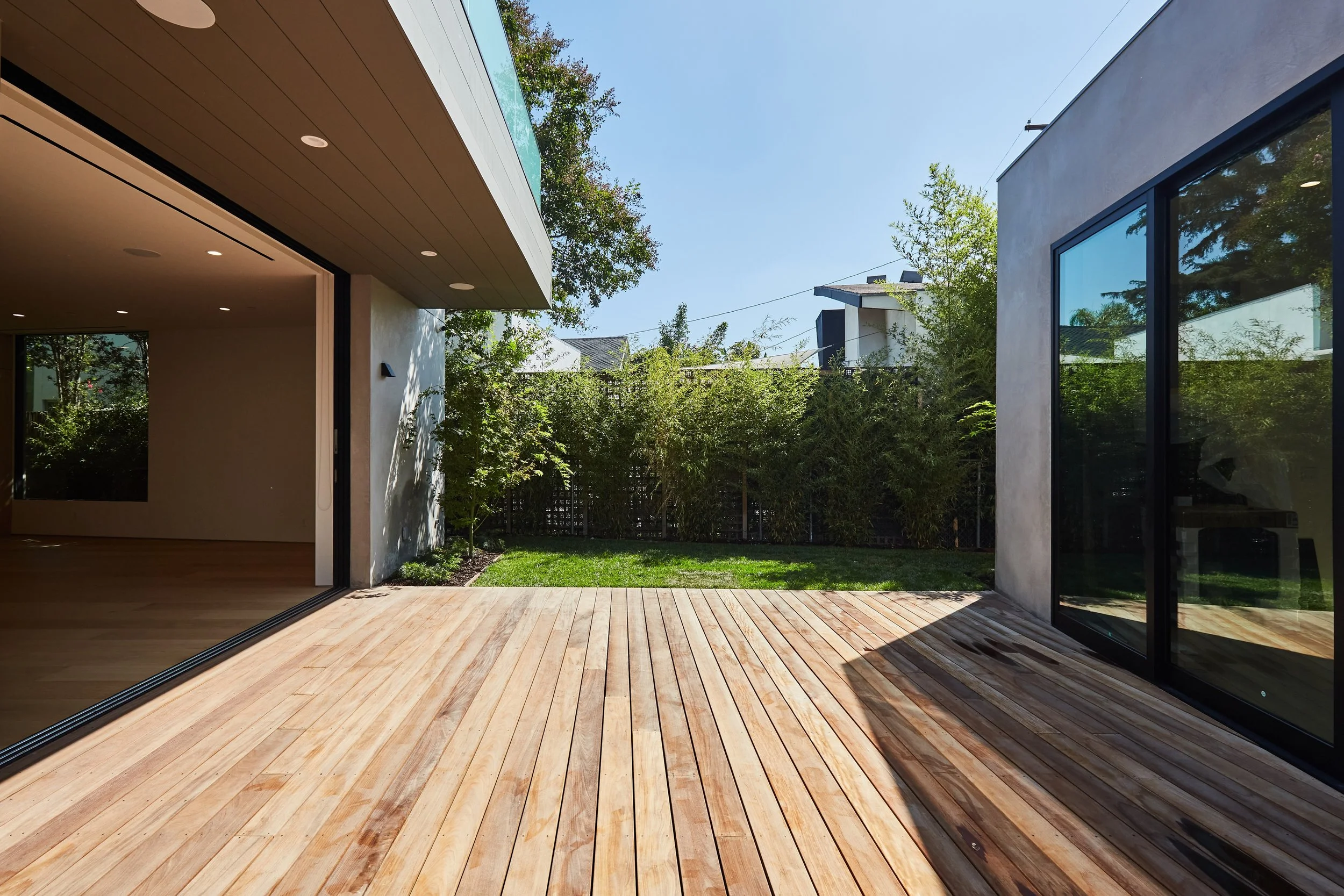 Private outdoor deck crafted for seamless California indoor-outdoor living, featuring warm wood decking and landscaped privacy by JBurton General Contractor.