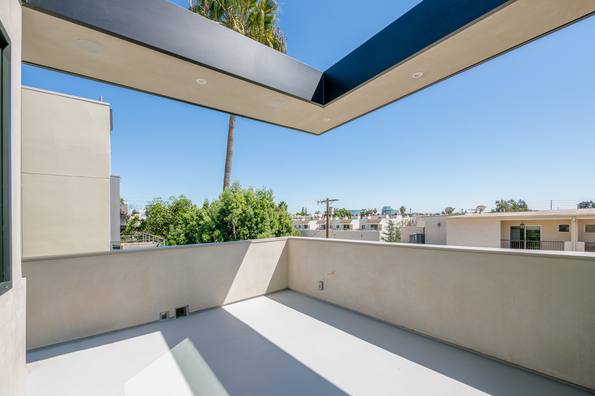 Covered outdoor terrace extending the living space with architectural shade, clean lines, and private open-air entertaining by JBurton General Contractor.