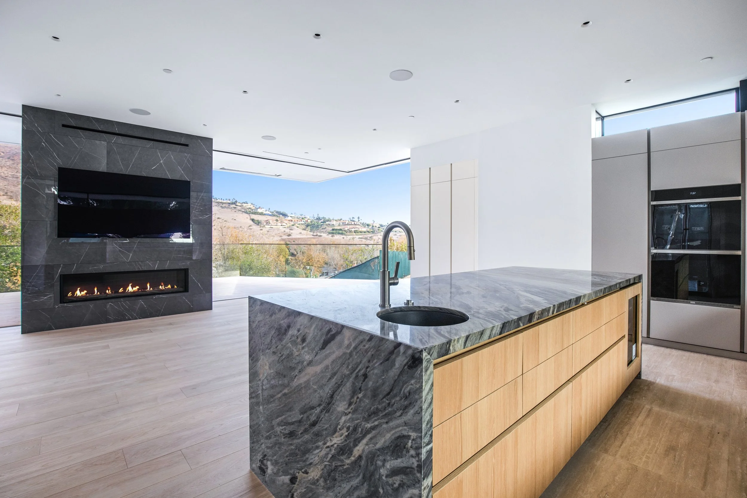 Gourmet kitchen with dramatic stone waterfall island and panoramic Malibu views by JBurton General Contractor.